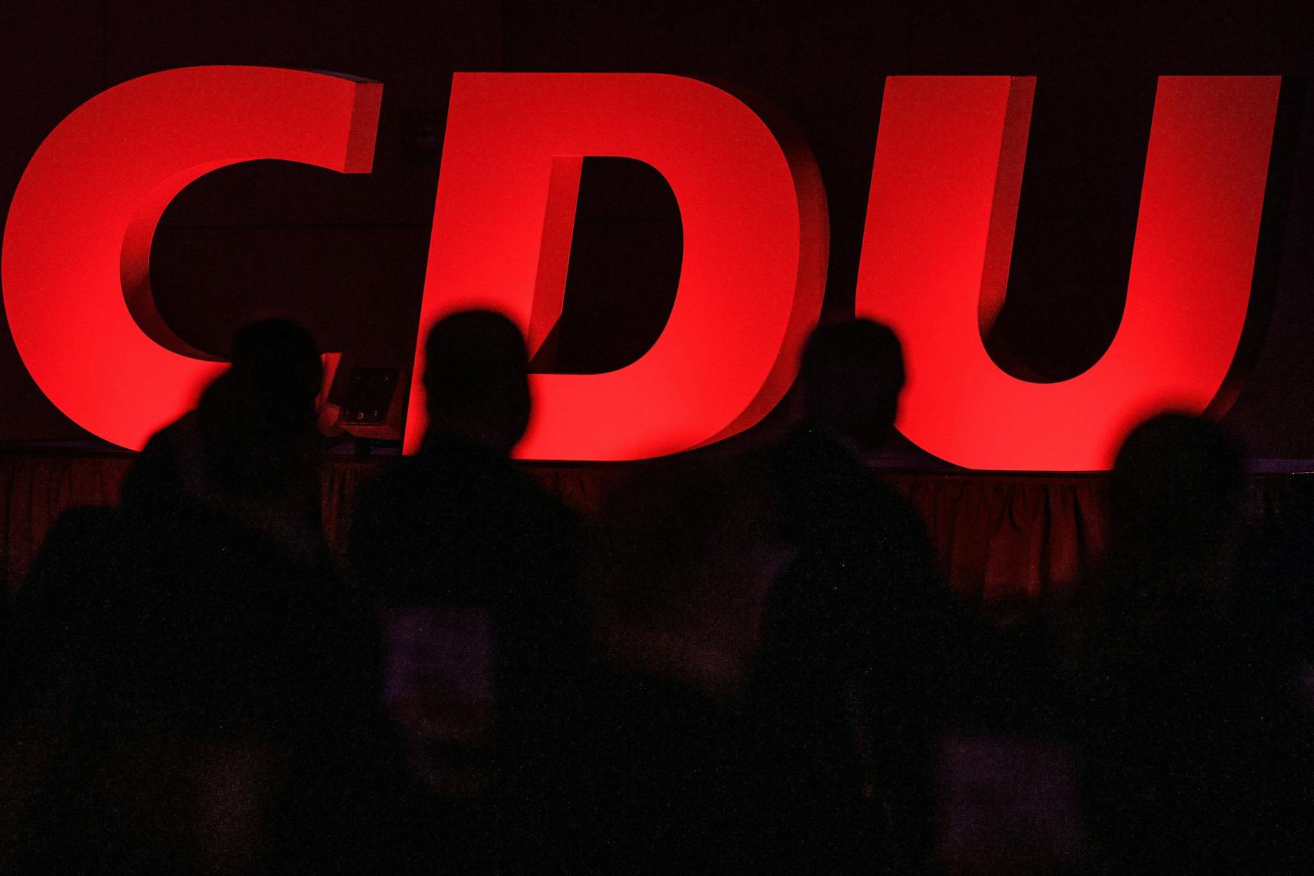 Delegierte sitzen beim Landesparteitag der CDU Hessen vor dem Logo der Partei.