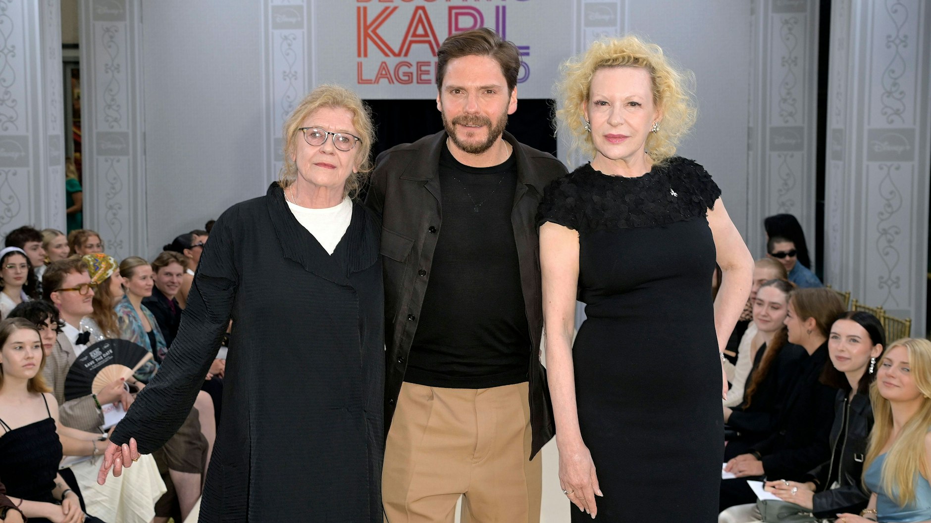 Der Schauspieler Daniel Brühl mit seinen Kolleginnen Lisa Kreuzer (l.) und Sunnyi Melles bei der Lagerfeld-Serienpremiere Ende Mai in Berlin. Dort lief er über einen Laufsteg.