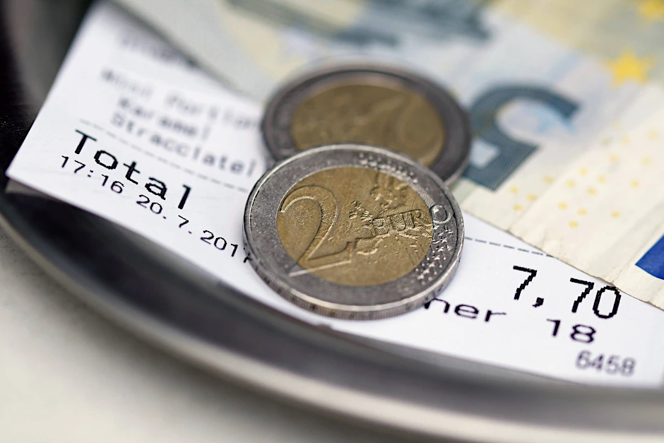Bargeld liegt auf dem Tisch zum Bezahlen der Rechnung. Wie viel Trinkgeld ist im Urlaub angebracht?