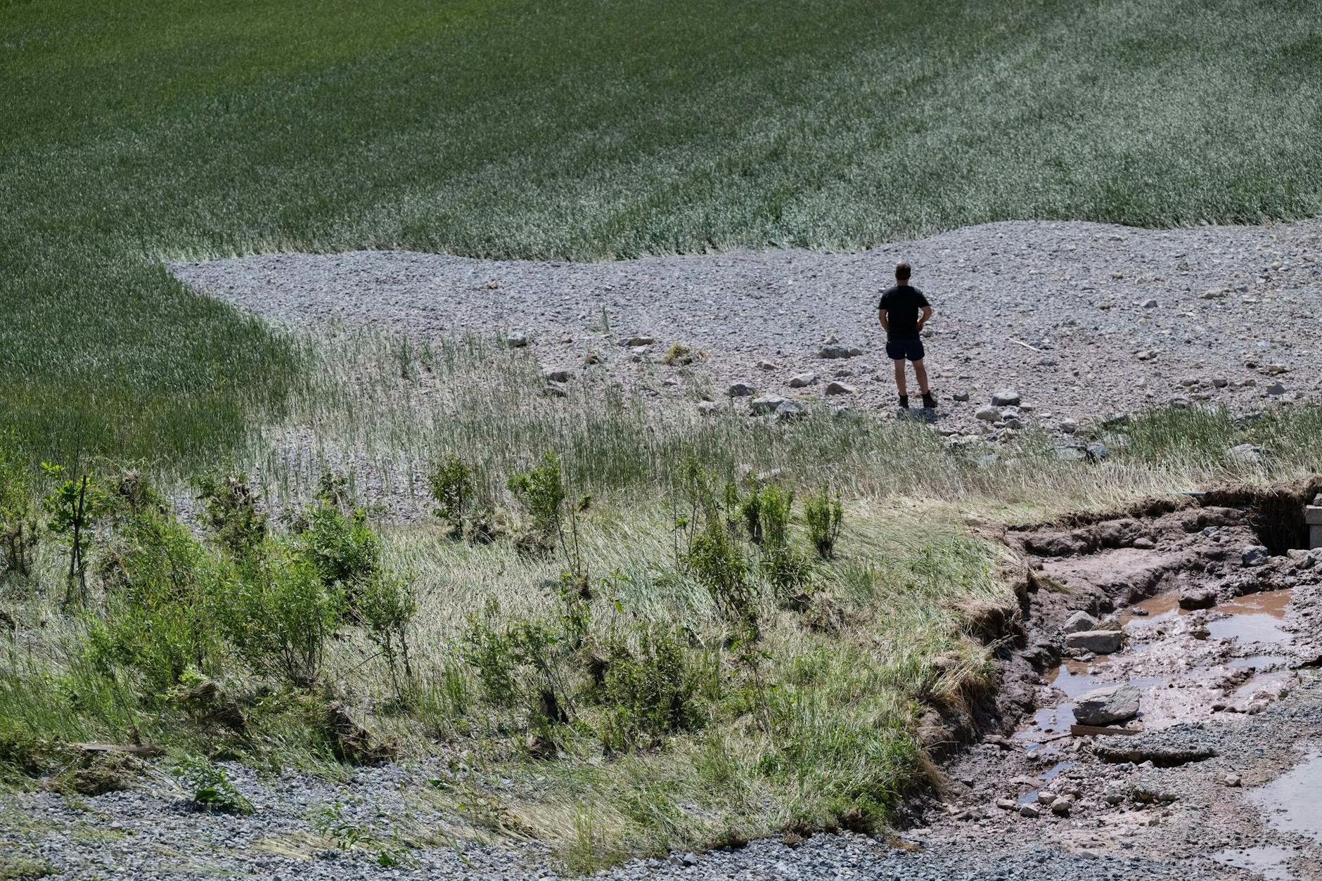 Einst Weizenfeld, dann überschwemmt und jetzt bedeckt von Geröll: Ein Landwirt begutachtet, was noch von seinem Acker bei Rudersberg übrig ist. Auch an anderen Orten in Baden-Württemberg beginnen nach Dauerregen und Überschwemmungen die Aufräumarbeiten.