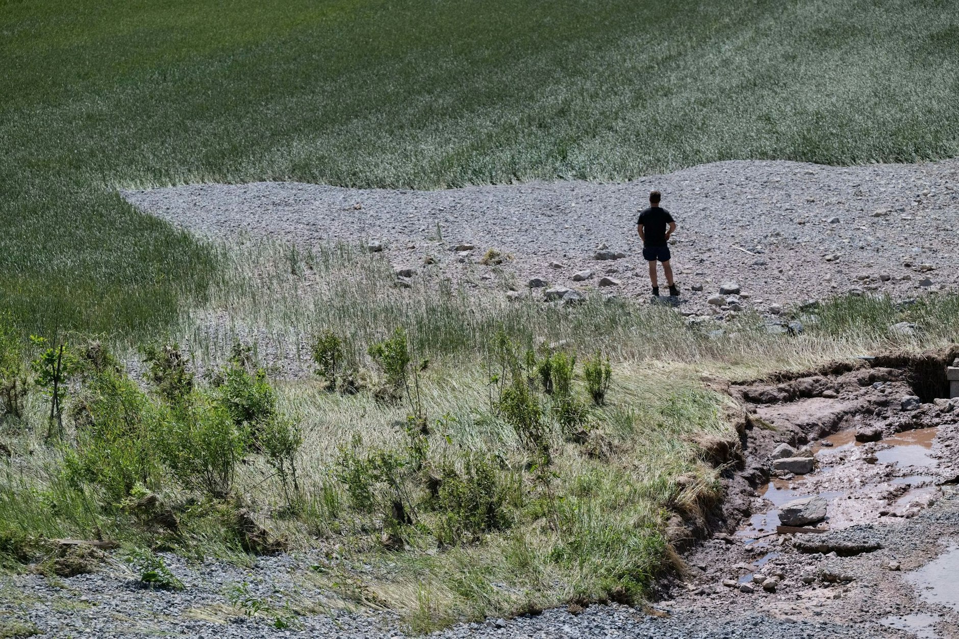 Einst Weizenfeld, dann überschwemmt und jetzt bedeckt von Geröll: Ein Landwirt begutachtet, was noch von seinem Acker bei Rudersberg übrig ist. Auch an anderen Orten in Baden-Württemberg beginnen nach Dauerregen und Überschwemmungen die Aufräumarbeiten.  