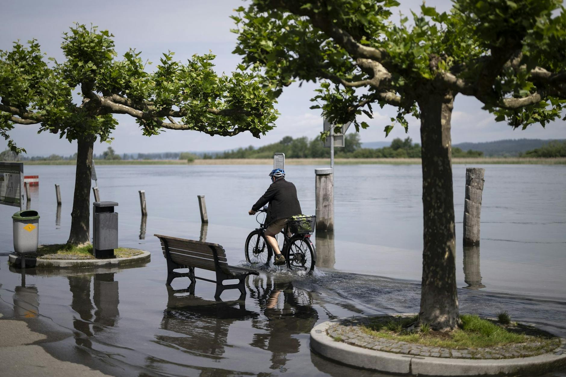 Entlang der Uferpromenade im schweizerischen Thurgau fährt ein Mann mit seinem Fahrrad durch Wasser. Der Seerhein, ein Zufluss des Bodensees, ist über seine Ufer getreten.