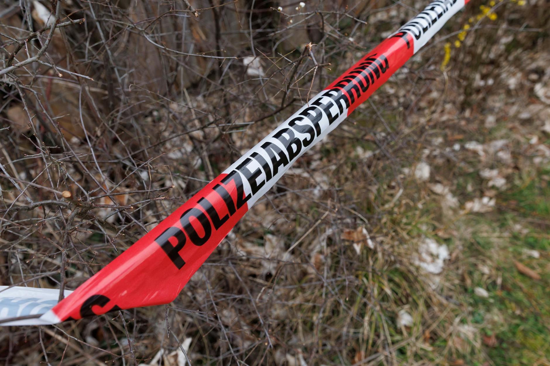 Rot-weißes Flatterband der Polizei ist an einem Tatort zu sehen.