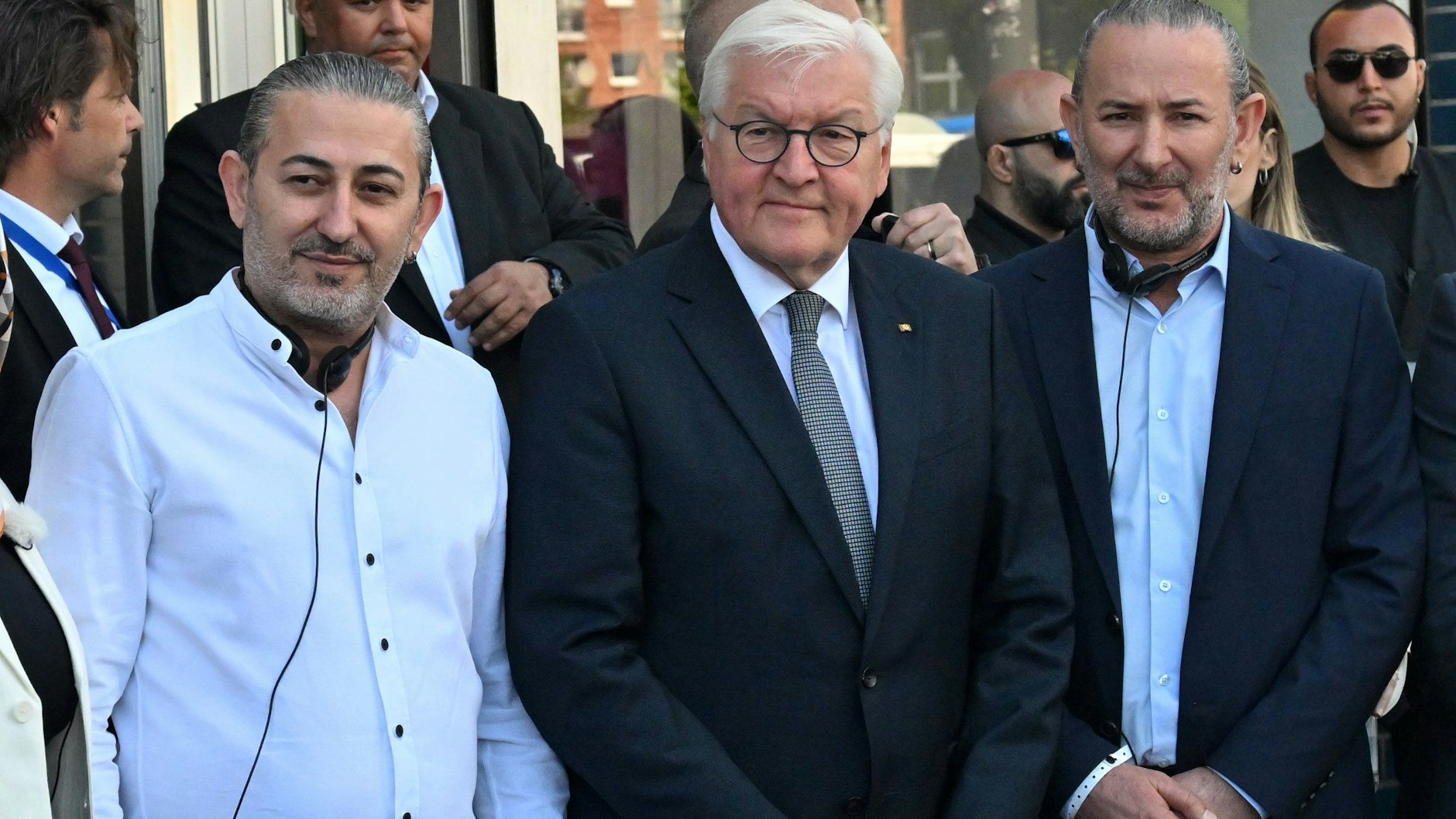 Bundespräsident Frank-Walter Steinmeier (M) steht mit Hasan Yildirim (l) und Özcan Yildirim vor ihrem Friseurgeschäft.