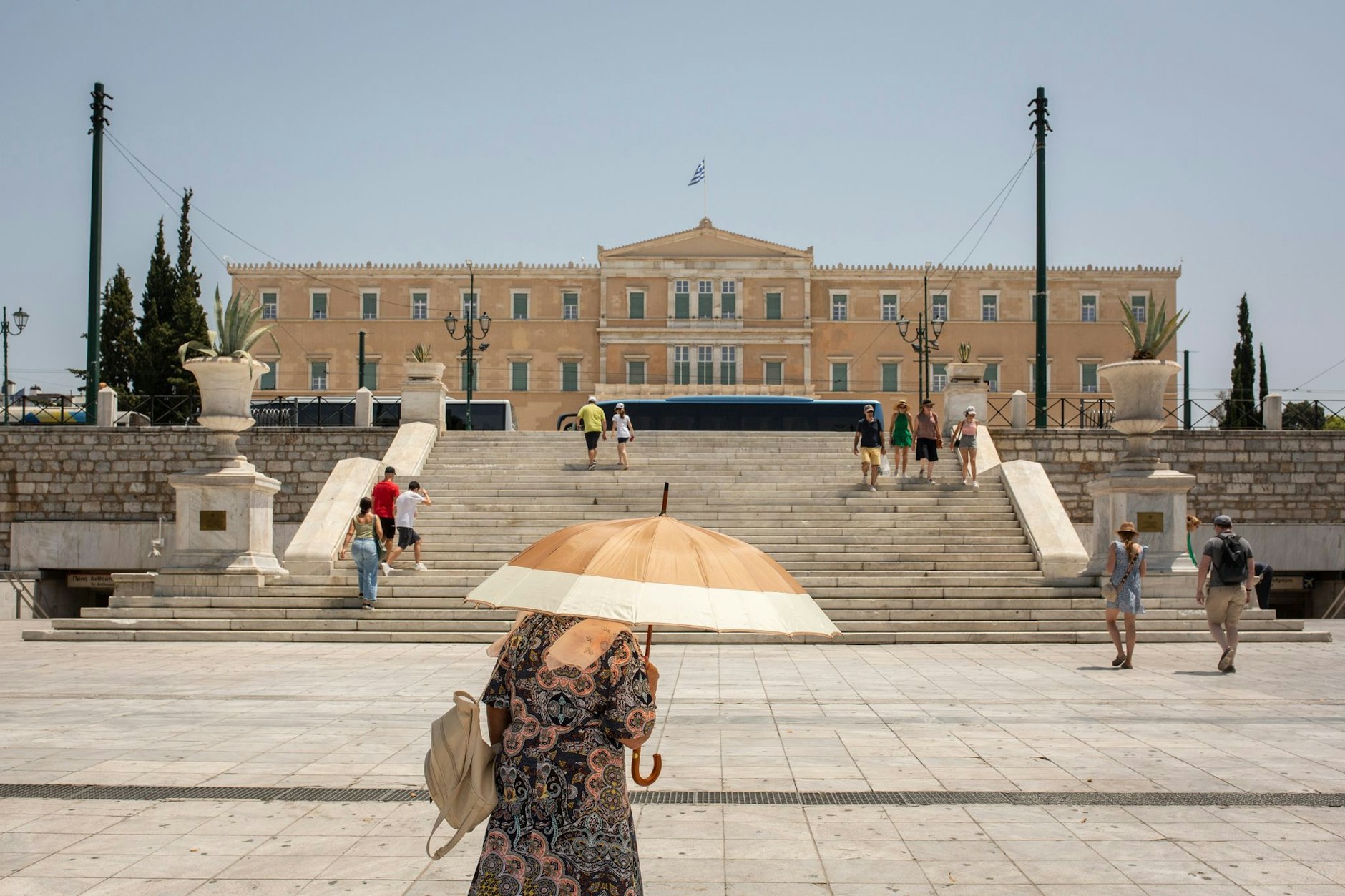 ARCHIV - Eine Frau schützt sich mit einem Sonnenschirm  auf dem Syntagma-Platz in Athen vor der Sonne: Warme Luftmassen sorgen für Temperaturen von örtlich bis zu 45 Grad.  