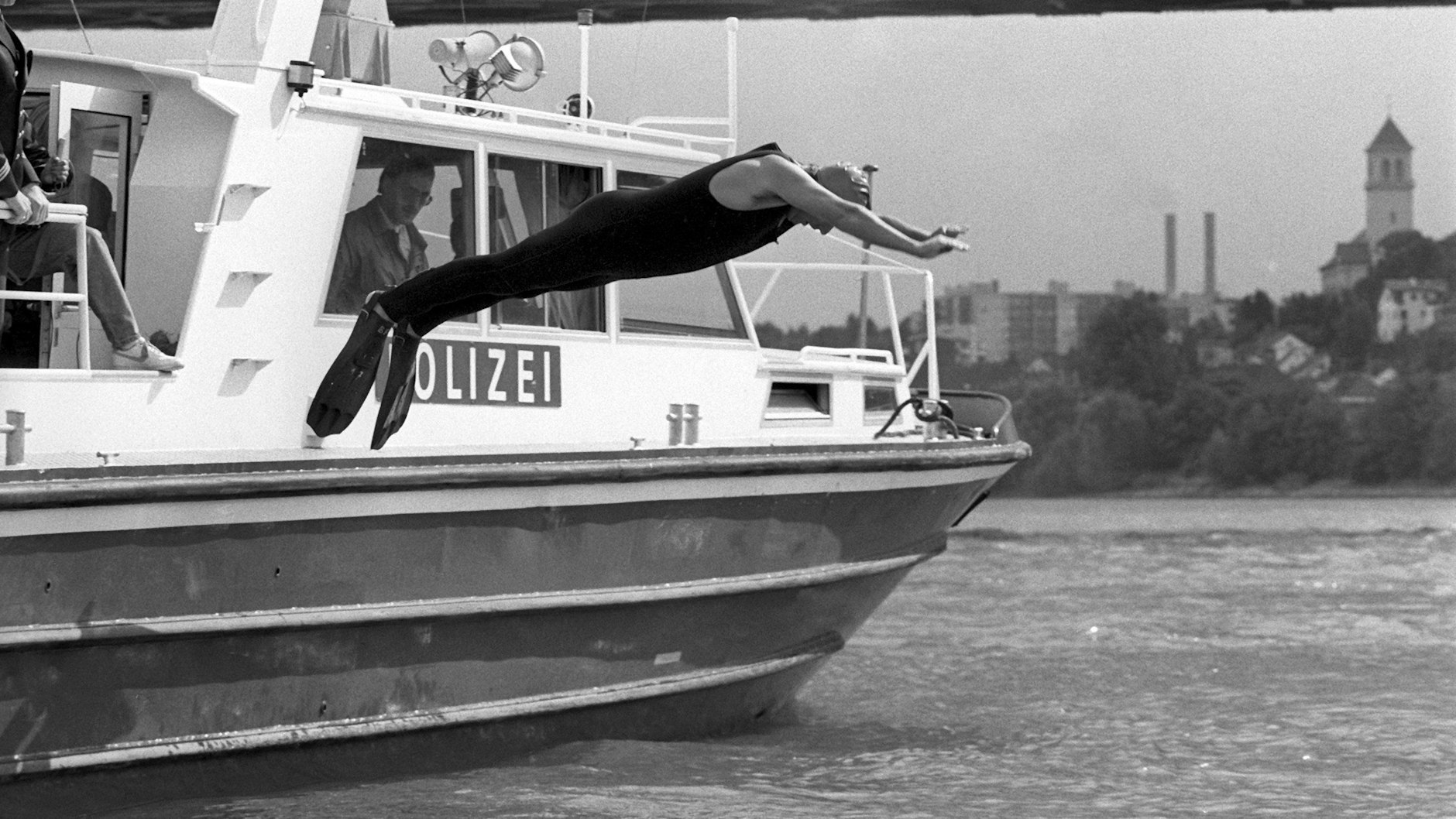 Mit Badekappe und Schwimmflossen springt Klaus Töpfer (CDU), damaliger Bundesumweltminister, von Bord eines Polizeibootes in den Rhein. Der damalige Bundesumweltminister wollte beweisen, dass nach einer Reihe von Chemikalieneinleitungen die Flüsse wieder regenerierten.