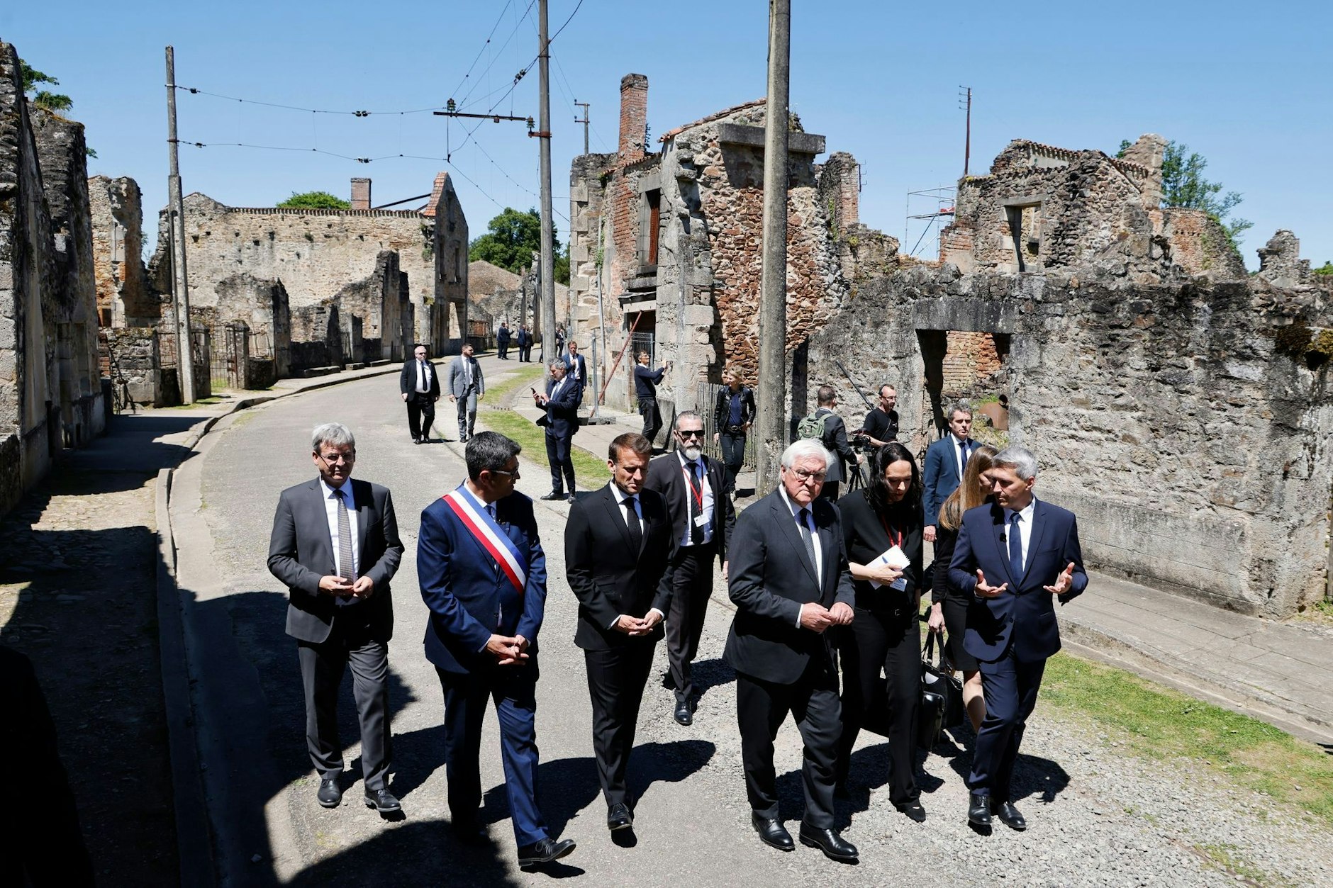 Der französische Präsident Emmanuel Macron und der deutsche Bundespräsident Frank-Walter Steinmeier gehen an Ruinen in Oradour-sur-Glane vorbei.  