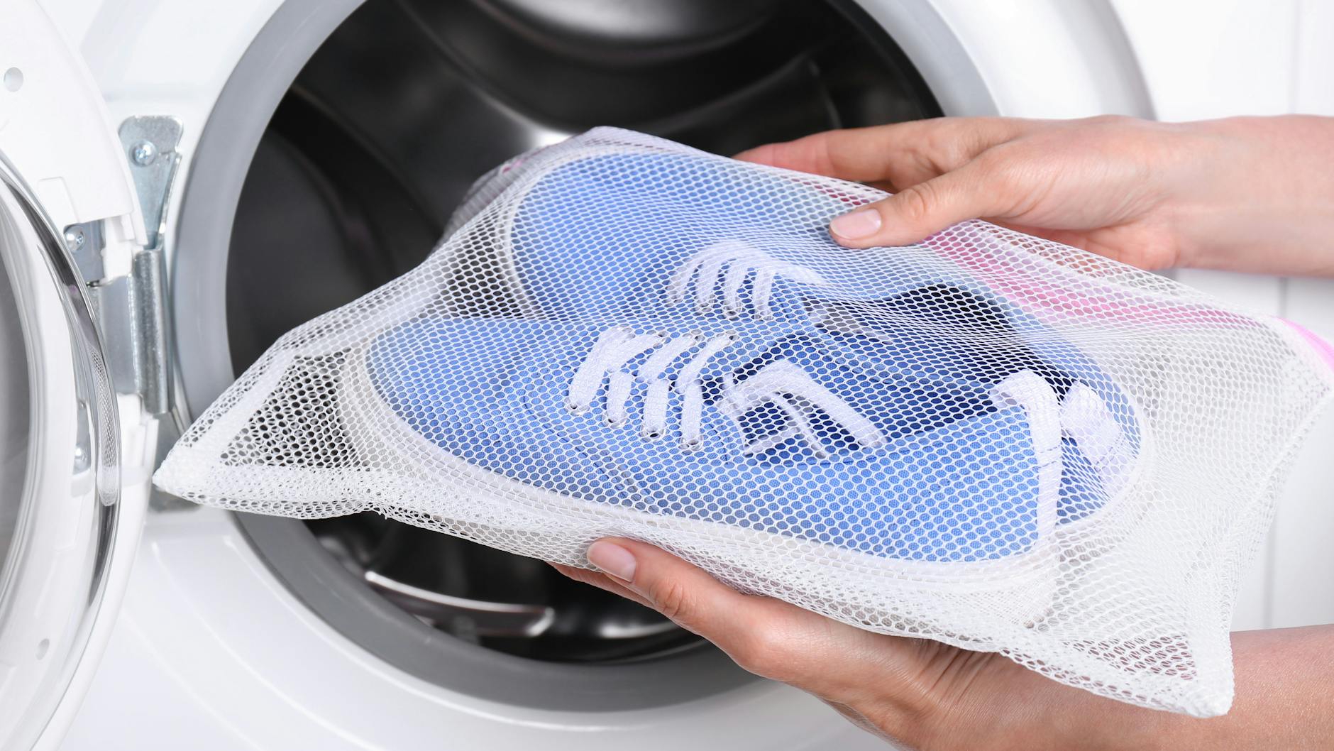 Zum Schutz der Sneaker die Schuhe in ein Wäschenetz oder einen alten Kopfkissenbezug geben. Schnürsenkel sollten vorher herausgezogen und extra mit ins Netz gelegt werden.