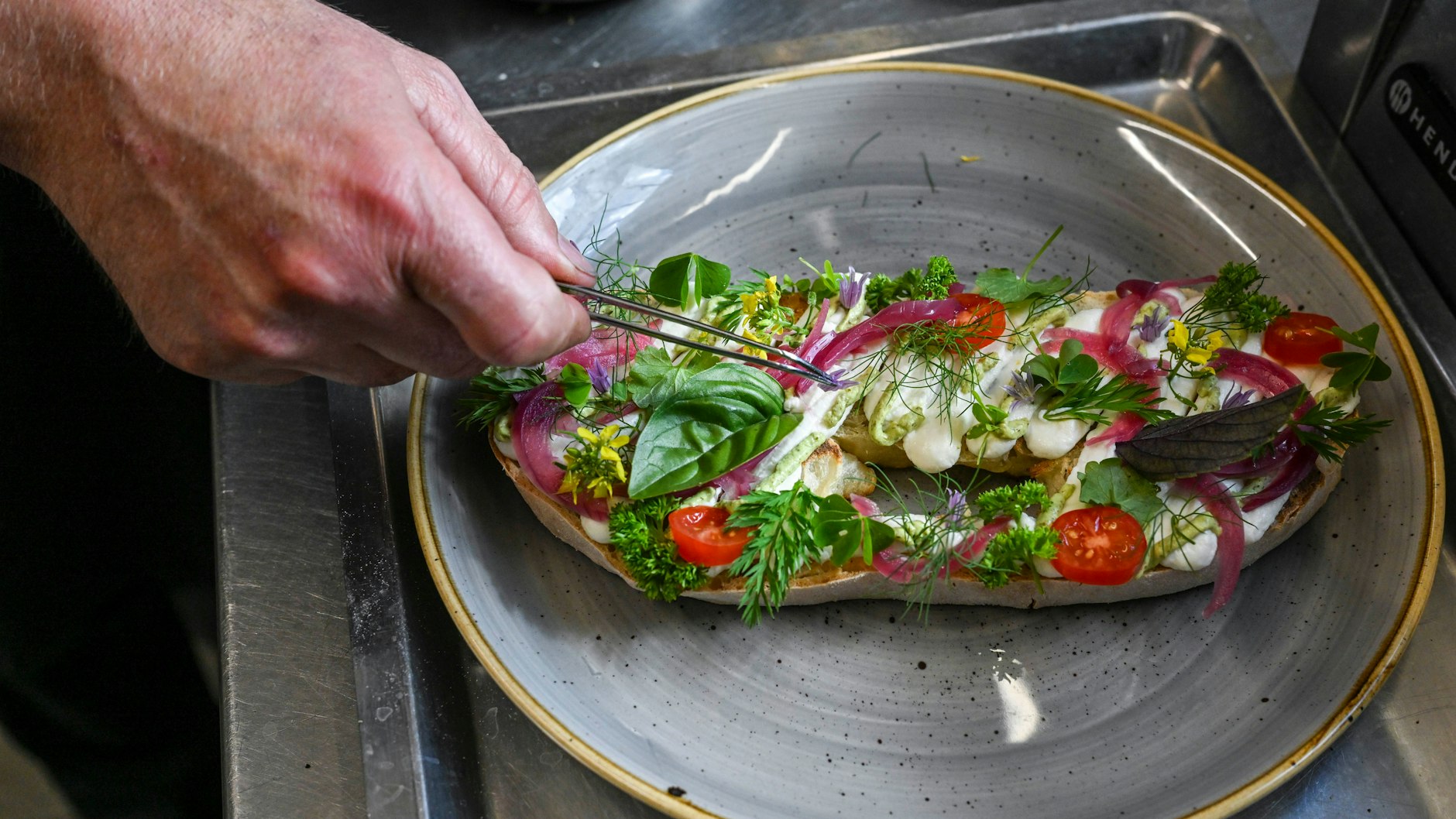 Marcus Kümmel bereitet ein Knoblauchbrot aus selbstgebackenen Brot, Aioli und Kräutern der Saison vor.&nbsp;