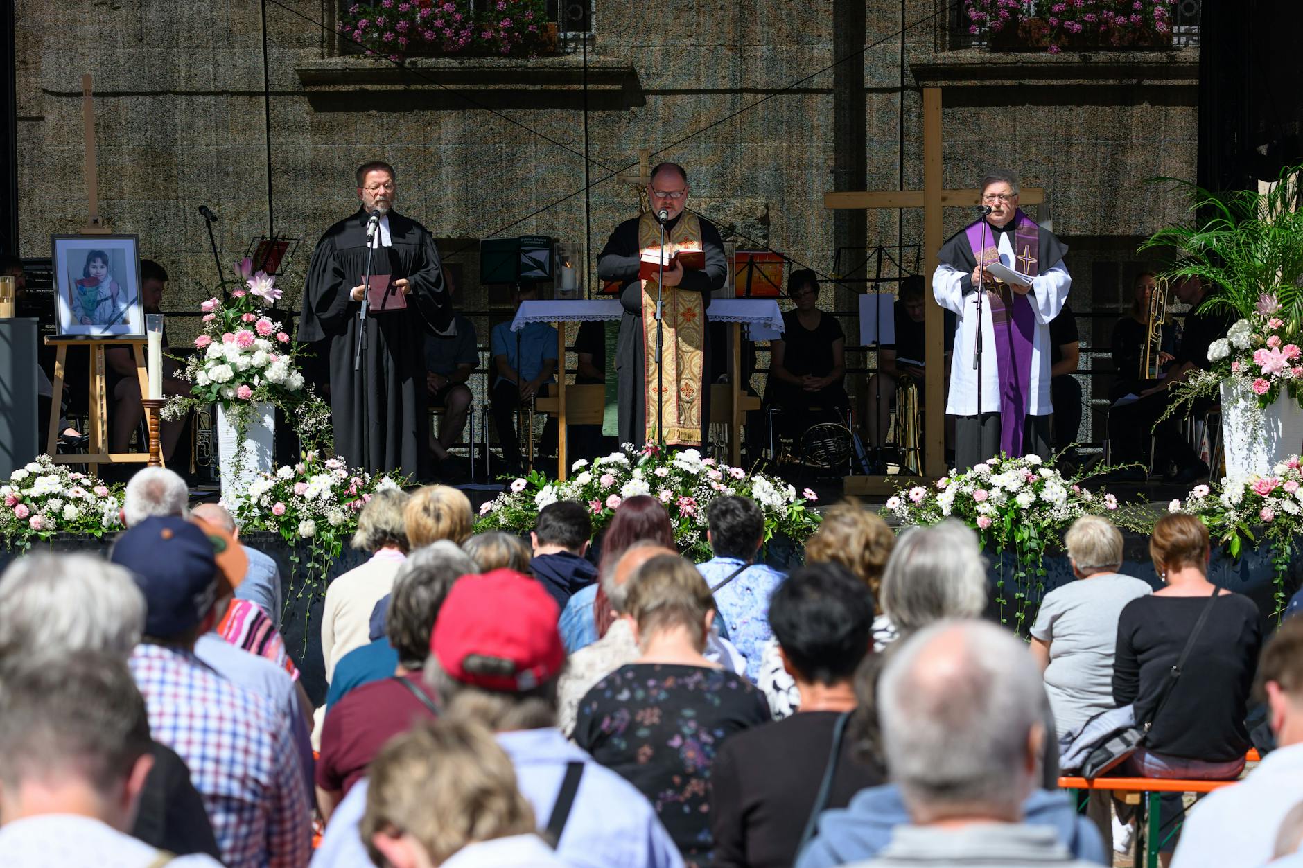 Der evangelische Pfarrer Lutz Behrisch (l-r), Bogdan Luka, Pfarrer der ukrainischen Kirche in Dresden, und der katholische Pfarrer Steffen Börner stehen bei einem Gottesdienst für die getötete Valeriia auf einer Bühne auf dem Obermarkt.