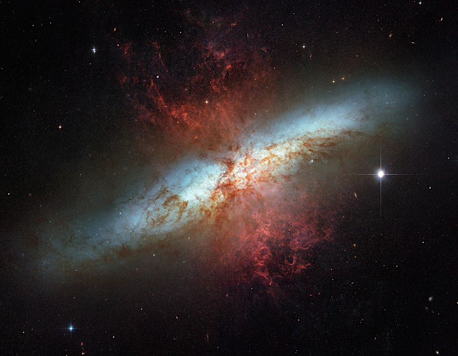 Blick auf die Starburstgalaxie Messier 82, auch „Zigarrengalaxie“ genannt, etwa zwölf Millionen Lichtjahre von der Erde entfernt. Durch den „Vorbeiflug“ einer anderen Galaxie wurde sie stark verändert. Supernova-Explosionen haben zu einem Netz aus zerrissenen Wolken (Filamenten) und extrem turbulenten Wasserstoffschwaden senkrecht zur Galaxieachse geführt.
