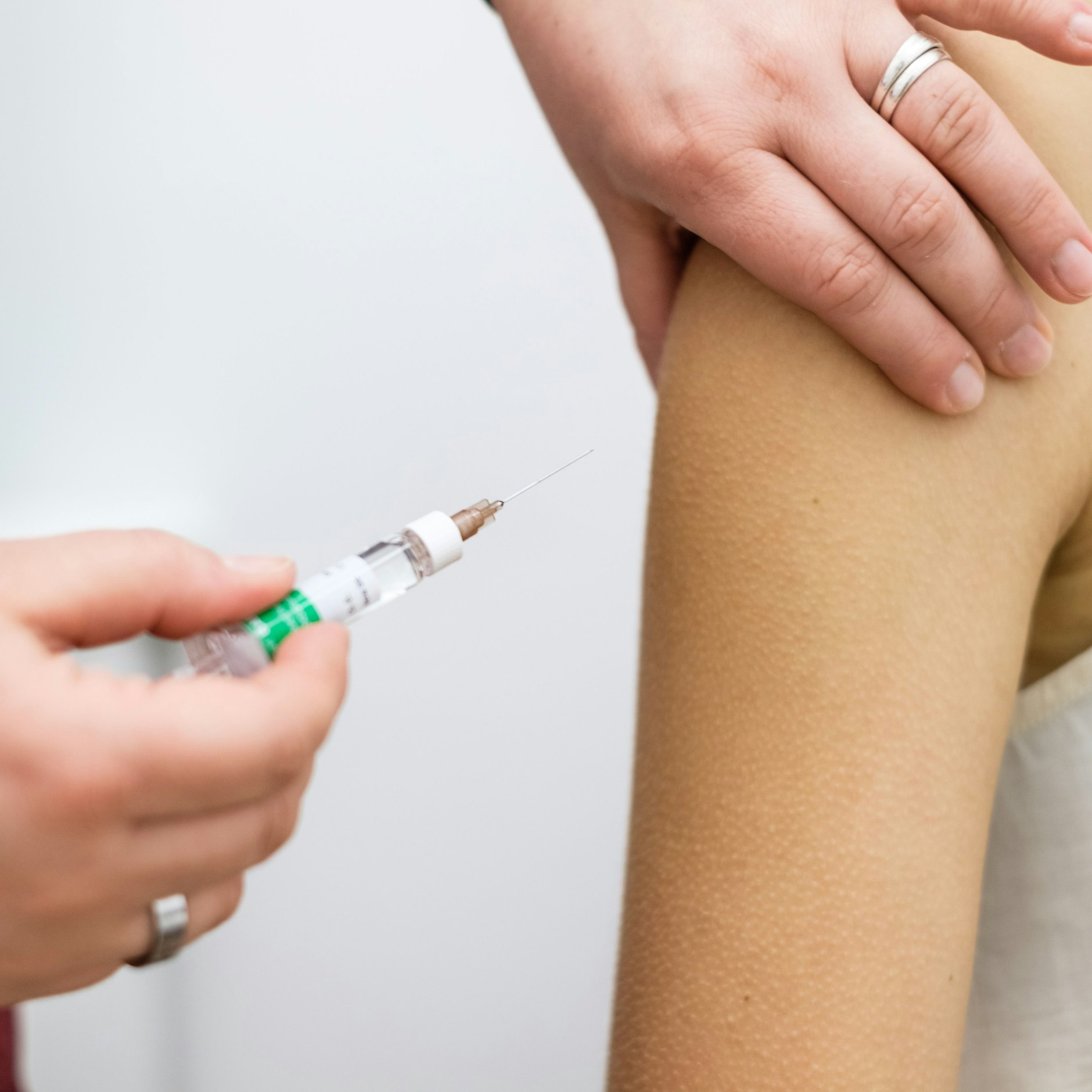 A medical assistant vaccinates a patient in a doctor's office.