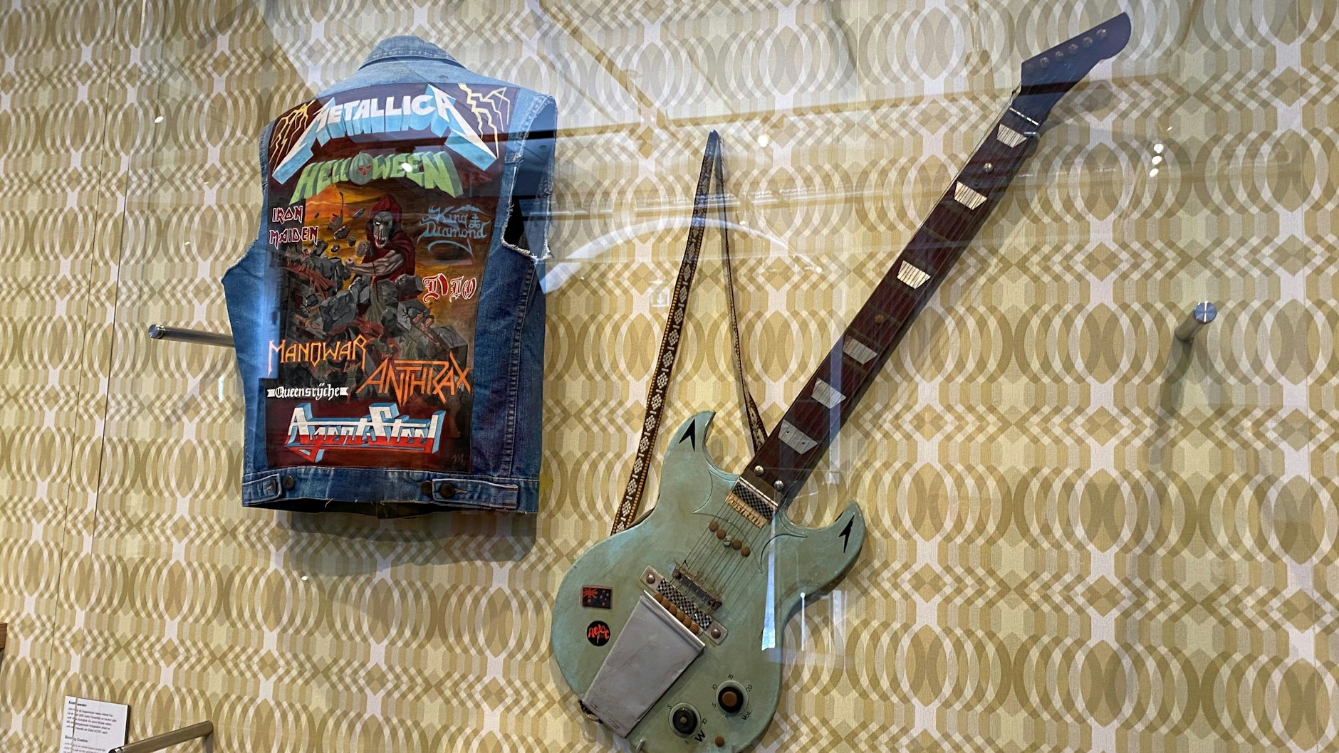 Mit solchen Jeans-Jacken mit den Logos der Lieblingsbands waren auch die Metal-Fans in der DDR unterwegs. Daneben eine nachgebaute Gitarre, mit der ein Bastler AC/DC nacheiferte.