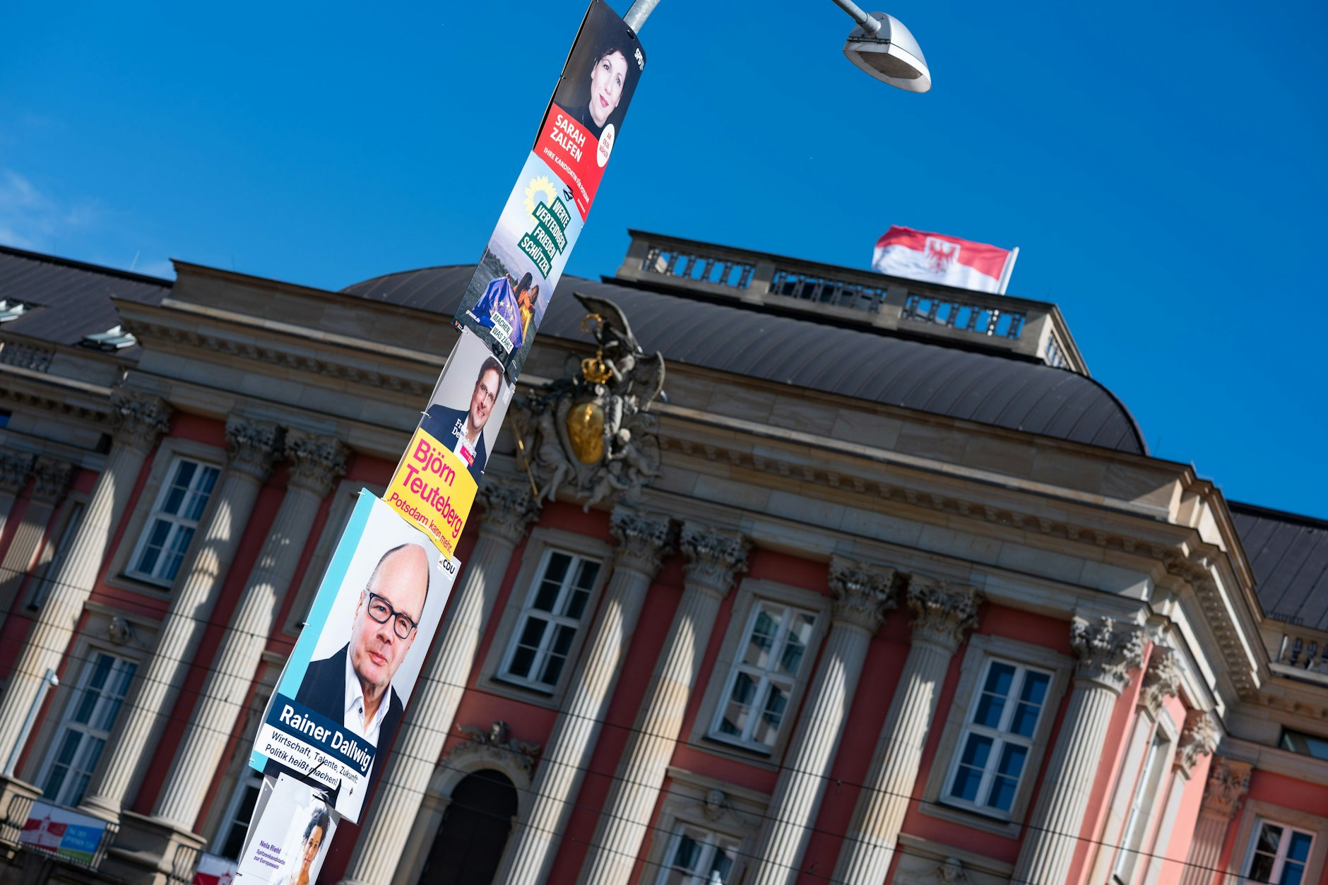 Plakate verschiedener Parteien hängen an einer Straßenlaterne vor dem Brandenburger Landtag.