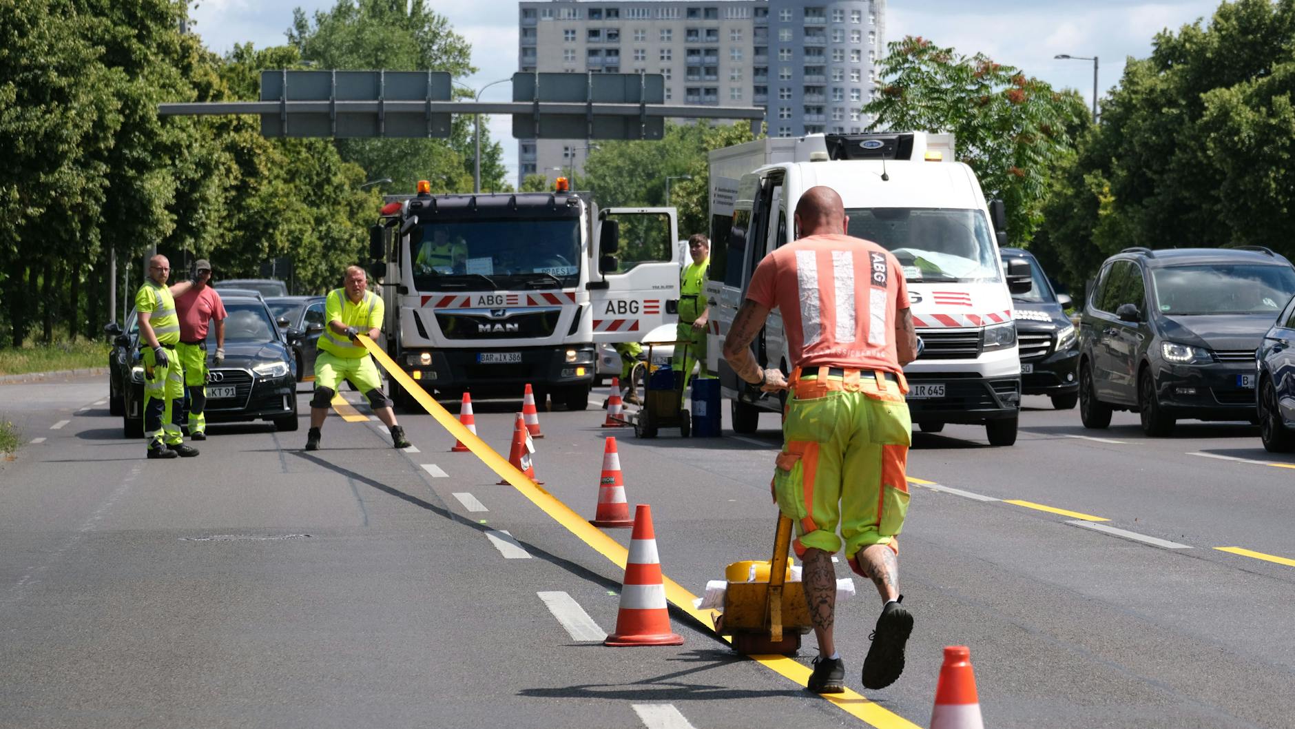 Bauarbeiter markieren am Montag die neue Spurführung auf der Straße Alt-Friedrichsfelde.