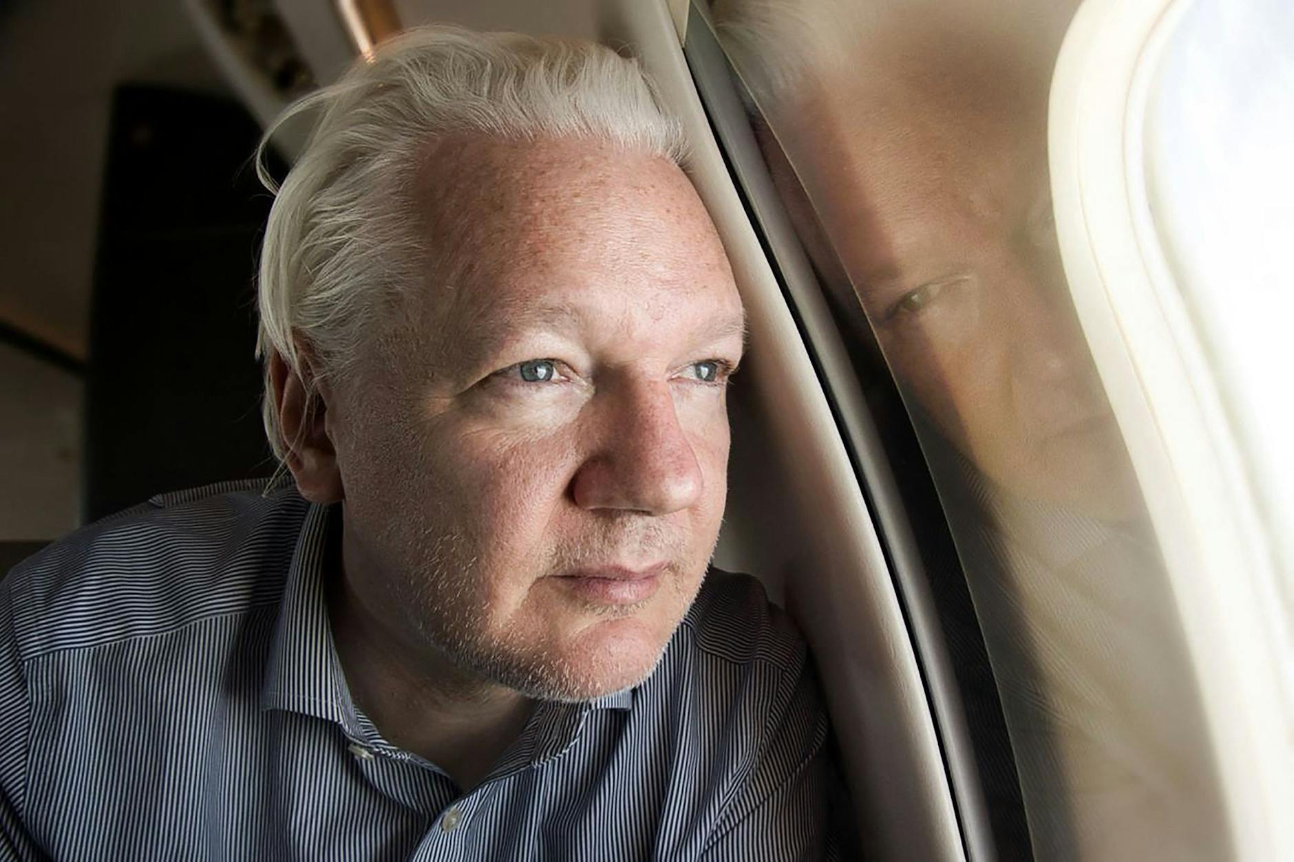 Julian Assange schaut aus dem Fenster des Flugzeugs auf der Reise von London nach Bangkok. Das Bild hat Wikileaks am 25. Juni über X geteilt.