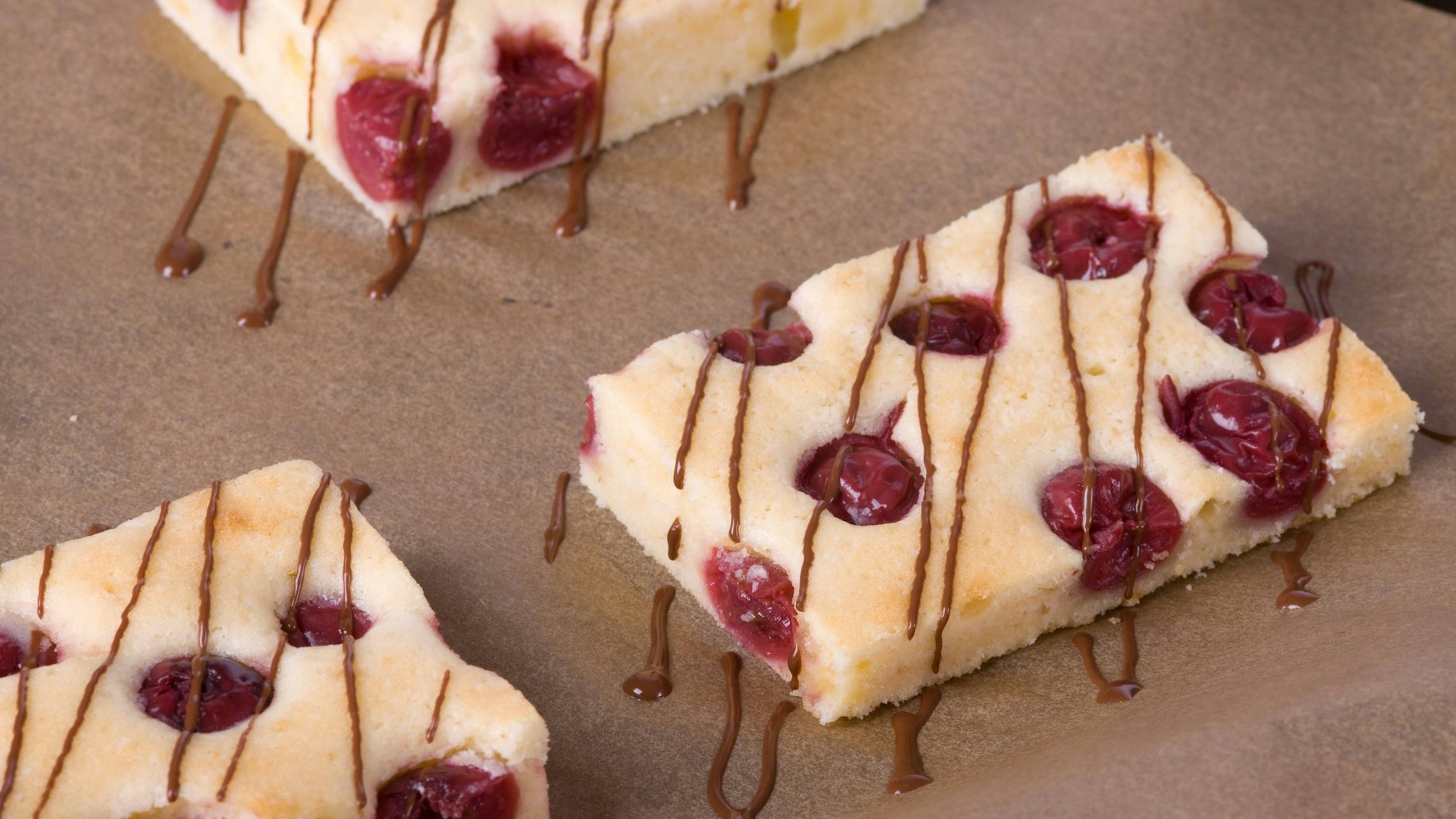 Das Rezept für Kirschkuchen sieht eine Glasur aus Schokolade vor. Wer es weniger süß mag, verteilt weniger Schokolade in einem schönen Streifenmuster über dem Kuchen. 