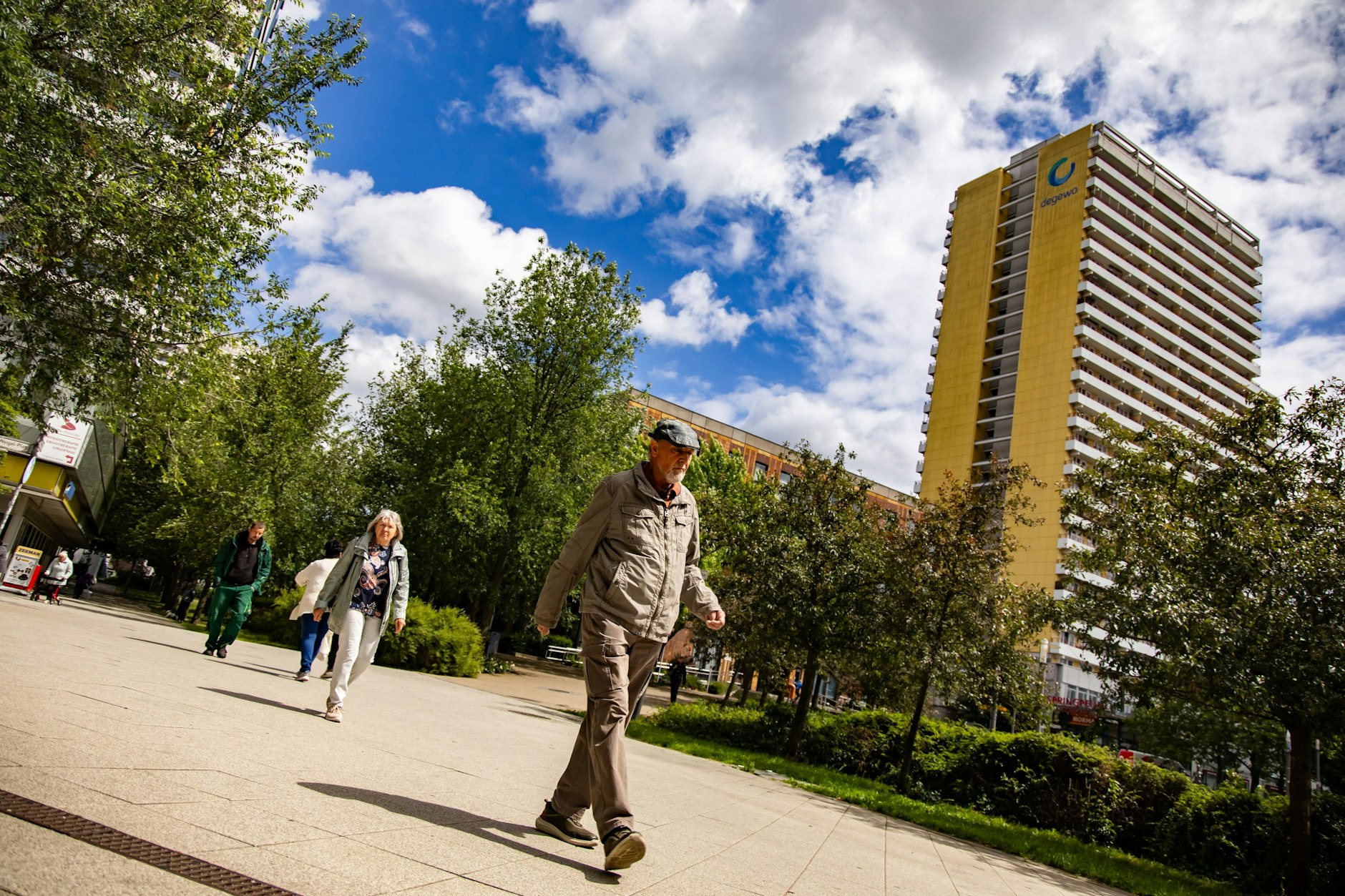 Menschen am Helene-Weigel-Platz in Marzahn. Im Hintergrund ein Haus der Degewo.&nbsp;