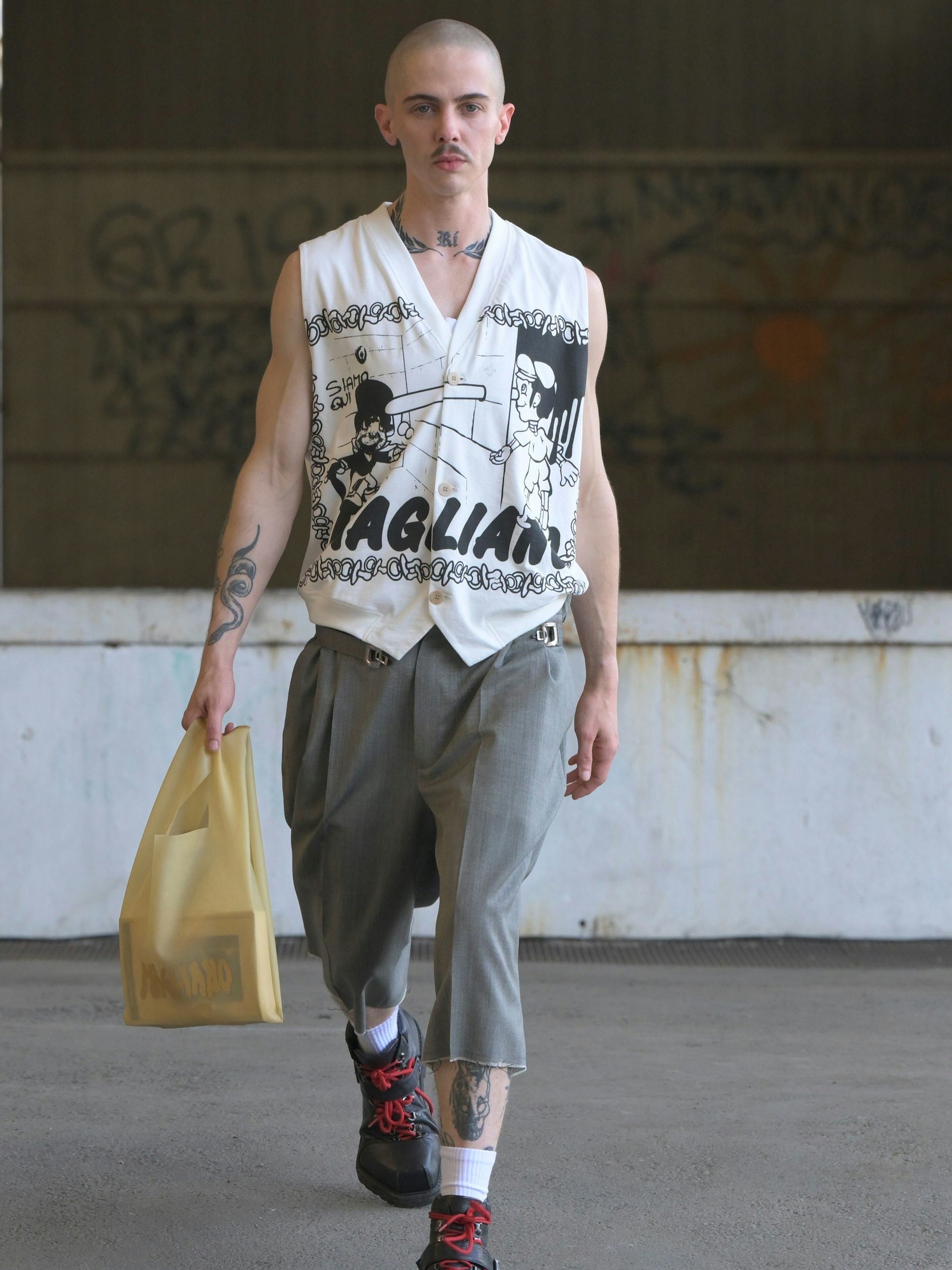 Dekonstruierte Sartoria bei den jungen Wilden von Magliano: abgeschnittene Hosenbeine und geknöpftes Tanktop plus Tattoos und Kahlkopf.