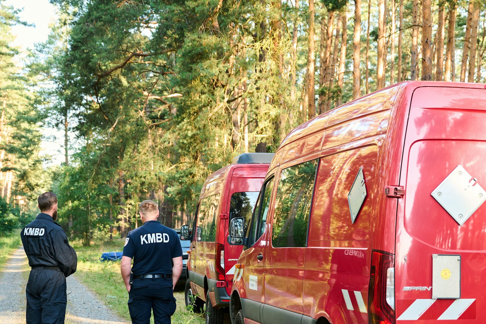 Zwei Mitarbeiter des Kampfmittelbeseitigungsdienstes stehen neben einem Fahrzeug im Wald nahe der Tesla-Fabrik. Geplant ist die Sprengung einer 250-Kilo-Bombe. Rund um die Weltkriegsbombe wurde ein Sperrkreis mit einem Radius von einem Kilometer eingerichtet.