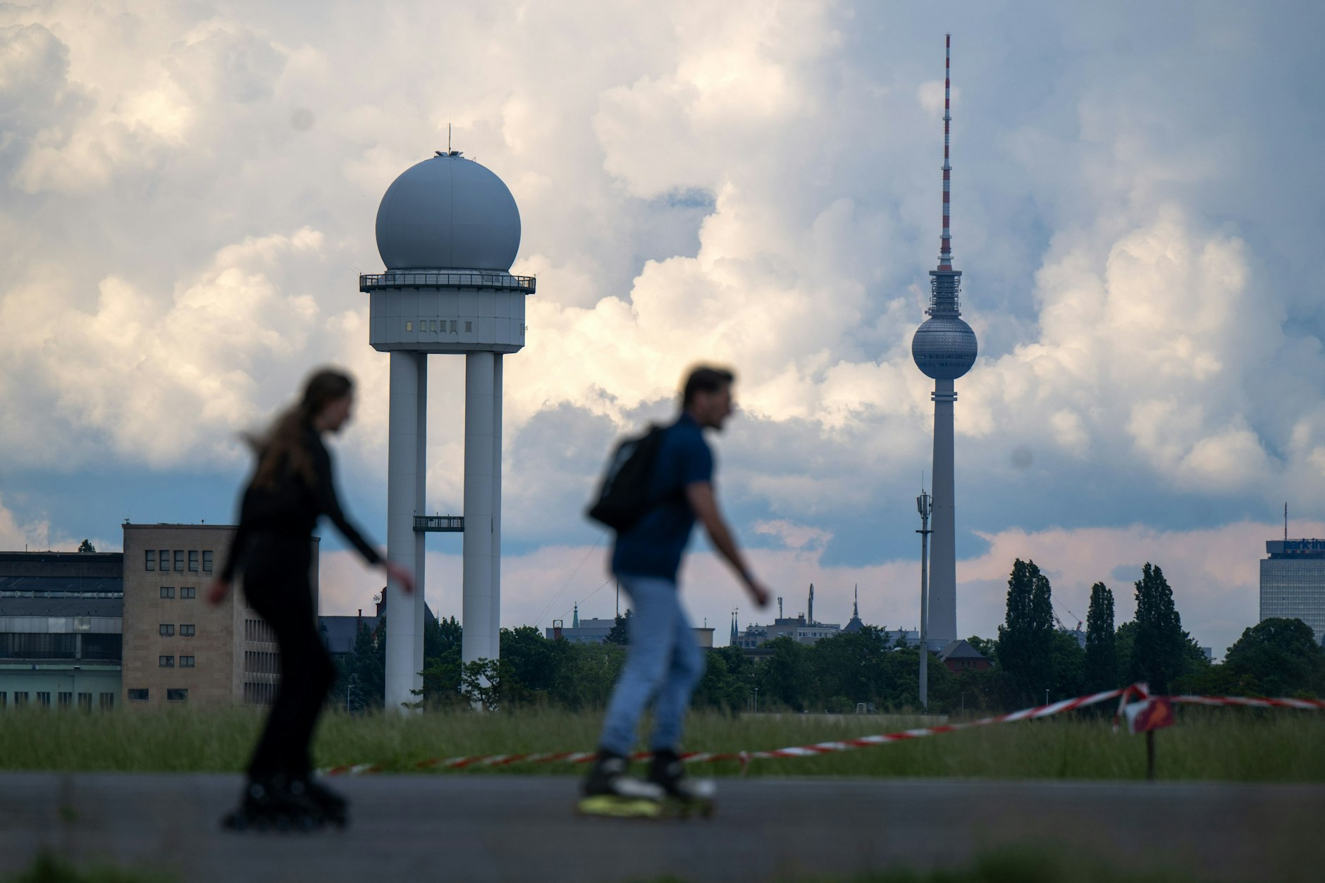 Regenwolken im Sommer: Zwei Inline-Skater fahren über das Tempelhofer Feld.