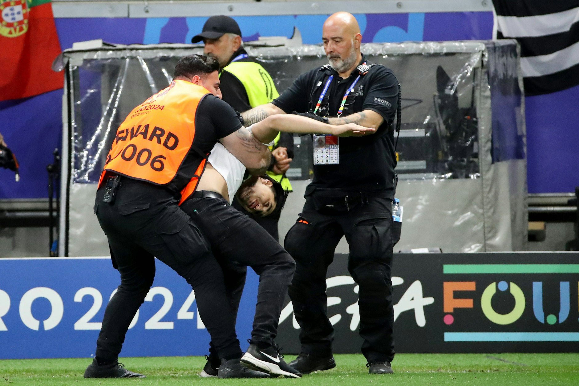 Hier stoppen Ordner korrekt mit Haltegriff einen Flitzer auf dem Rasen beim Portugal-Spiel. Doch im Innenraum spielte sich eine brutale Szene ab.