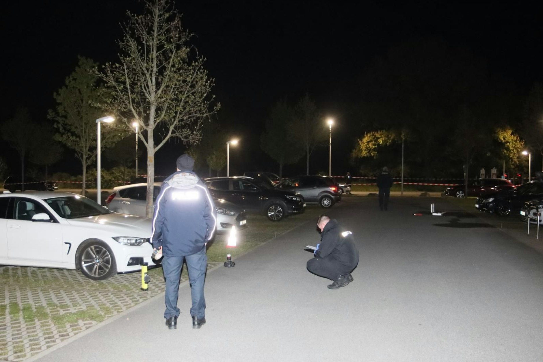 Polizisten suchen auf dem Parkplatz der JVA Heidering nach Hinweisen. Dort wurden am Abend des 23. April neun Autos von Mitarbeitern in Brand gesteckt.