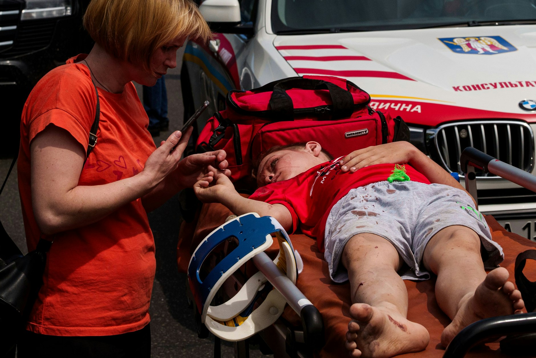 Eine Frau kümmert sich um ein Kind vor dem von russischen Raketen getroffenen Okhmatdyt-Kinderkrankenhaus.