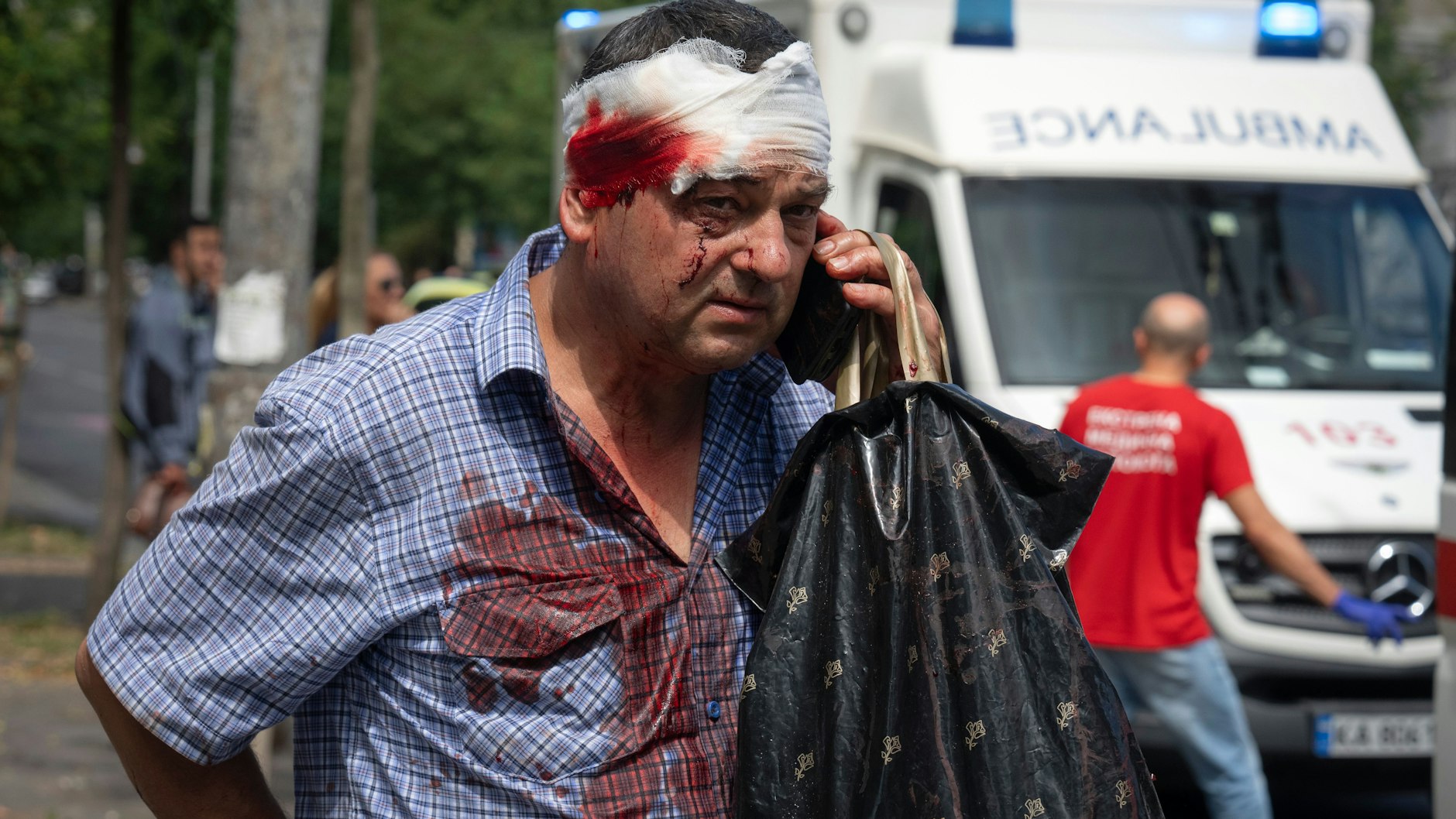 Ein verletzter Mann telefoniert auf der Straße.  