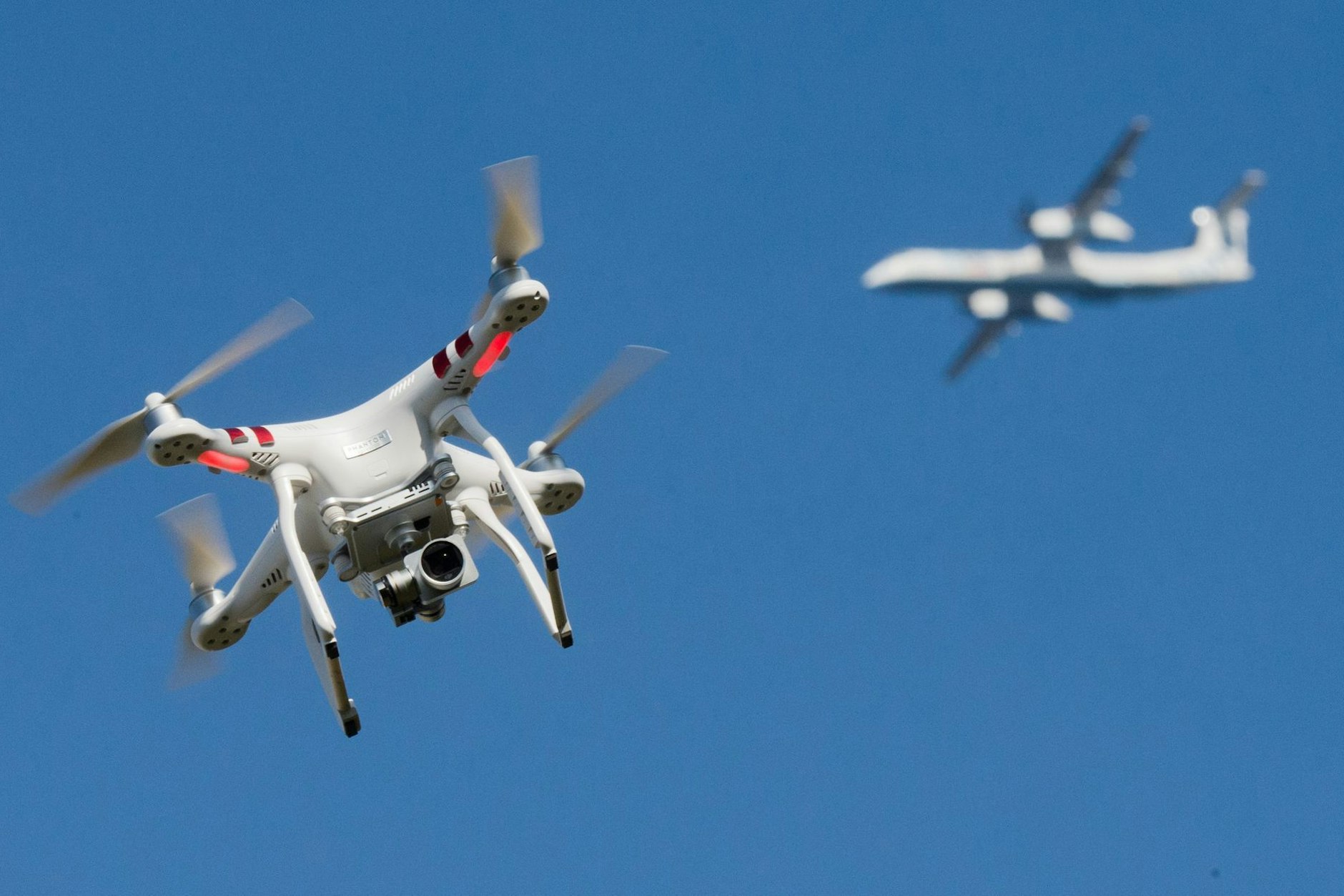 75 Vorfälle mit Drohnen im ersten Halbjahr  (Symbolbild) Eine private Drohne fliegt in weiter Entfernung von einem Flugzeug.