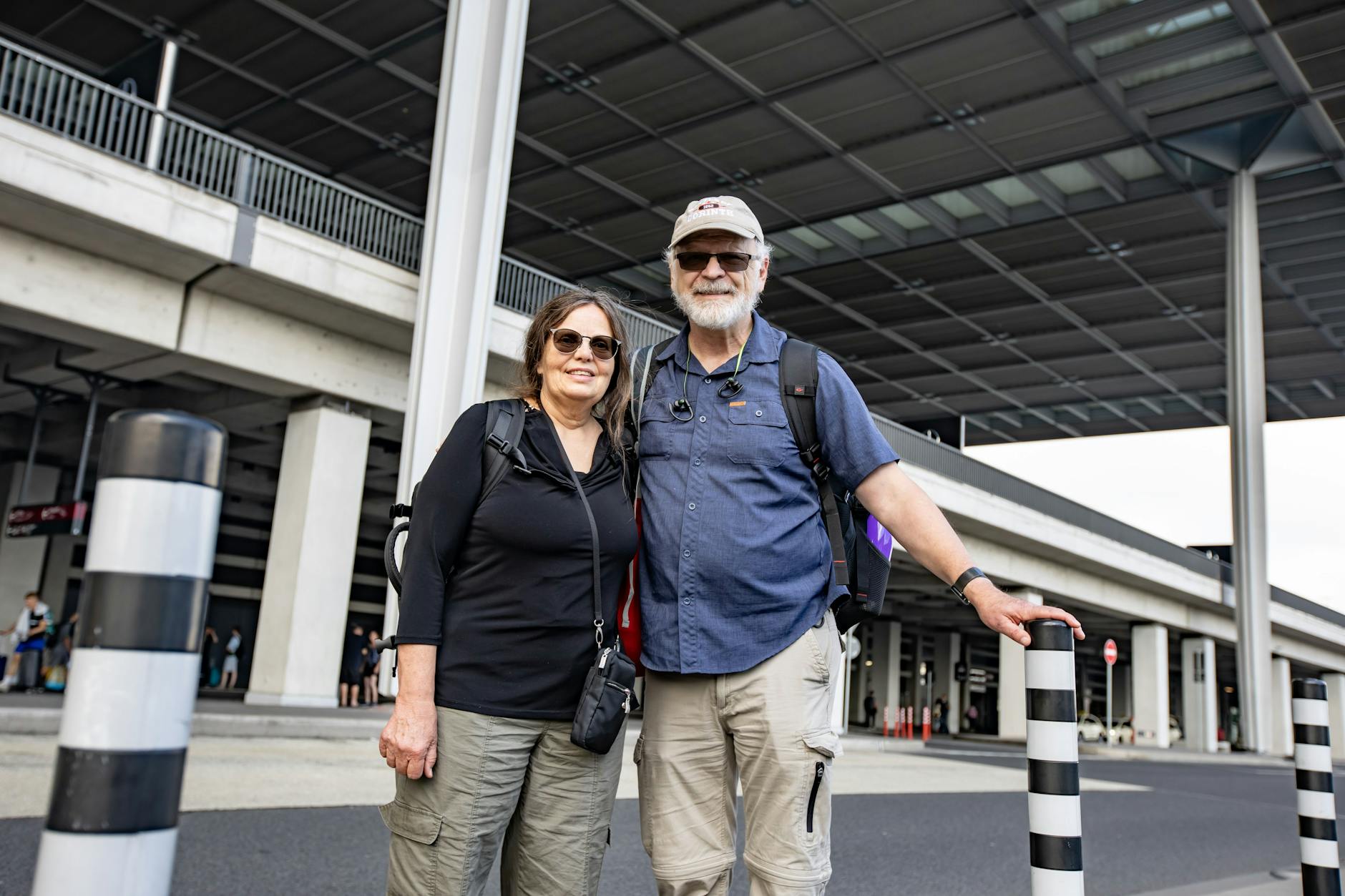 Carrie und James suchen vor dem BER-Flughafen nach dem richtigen Bus.