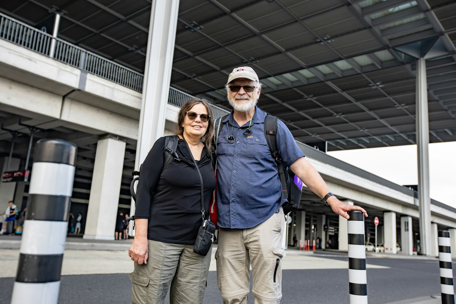 Carrie und James suchen vor dem BER-Flughafen nach dem richtigen Bus.