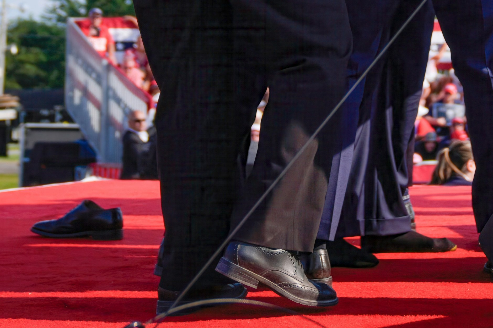 Der Fuß von Donald Trump ist durch die ihn umgebenden US-Geheimdienstmitarbeiter sichtbar, während sein Schuh (links) auf der Bühne einer Wahlkampfveranstaltung liegt.