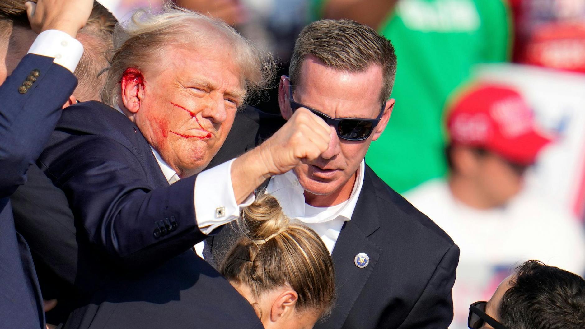 Agenten des US-Geheimdienstes Secret Service helfen dem ehemaligen US-Präsidenten Donald Trump von der Bühne bei einer Wahlkampfveranstaltung in Butler, Pennsylvania. Trump hat ein blutiges Ohr. 