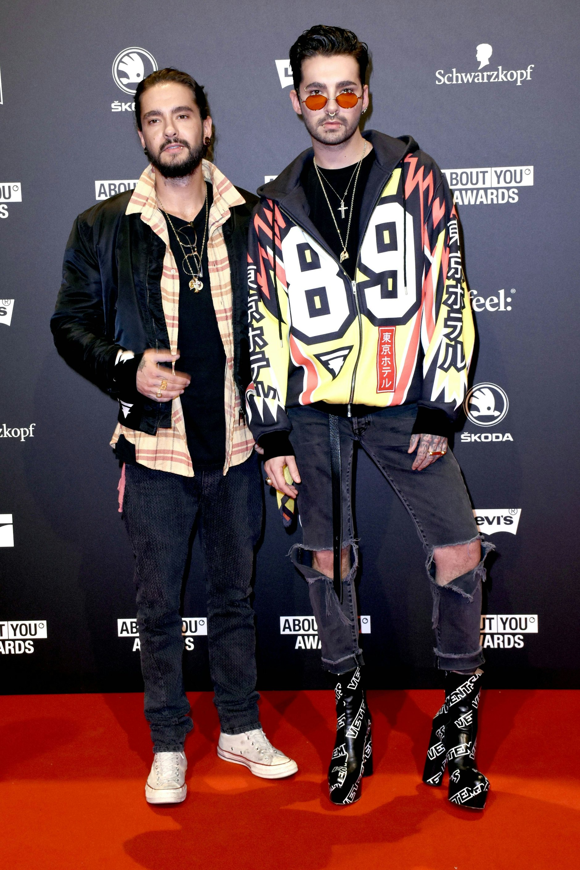 Tom und Bill Kaulitz 2018 bei der Verleihung der About You Awards in München. Bill trägt einen Zipper-Hoody seiner eigenen Modemarke MDLA (Magdeburg Los Angeles), die 89 steht für das Geburtsjahr der Zwillinge. Dazu trägt er Plateausstiefel von Vetements.