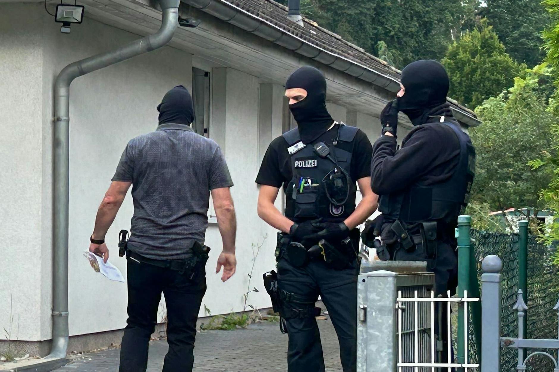 Vermummte Polizisten stehen vor einem Haus in Brandenburg. 
