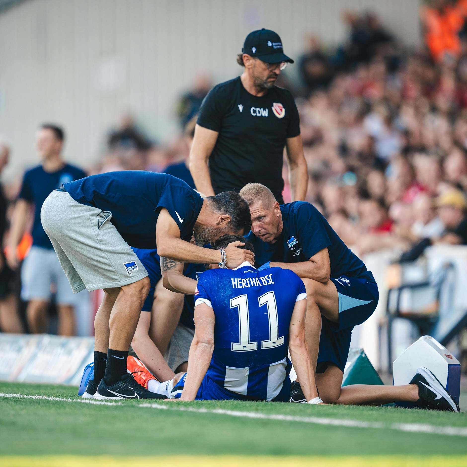 Herthas Trainer Cristian Fiel tröstet Reese am Spielfeldrand, als er am Knöchel behandelt wird.