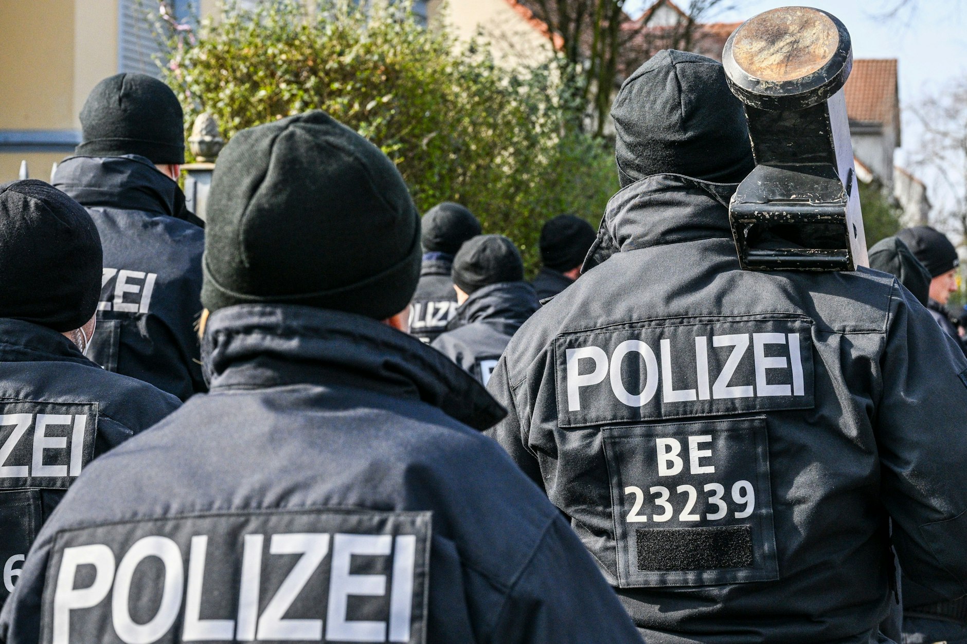 Polizisten, die eine Ramme bei sich tragen, sind in Buckow im Bezirk Neukölln vor einer Villa aus dem Clan-Milieu im Einsatz.