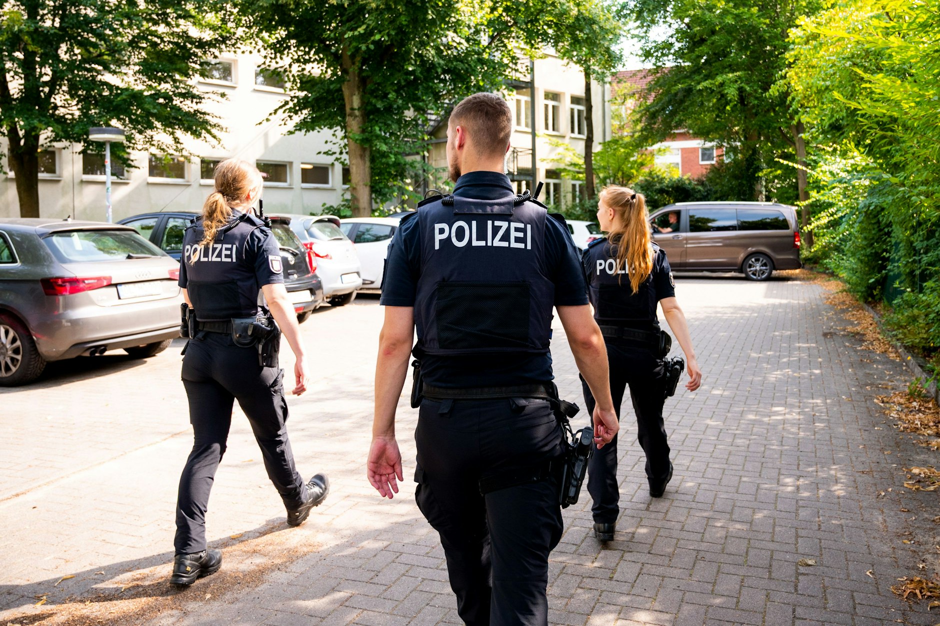 Auf diesem Platz wurde ein Dozent niedergestochen: Polizisten gehen über den Parkplatz der Schule in Wedel.