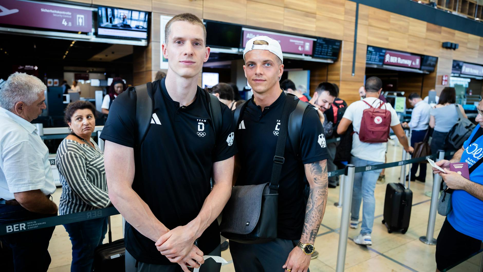 Lars Rüdiger (l), Timo Barthel, zwei deutsche Olympiasportler im Wasserspringen, warten im BER vor der Sicherheitskontrolle. Nach stundenlanger Störung ist der Betrieb am BER gegen Freitagmittag langsam wieder angelaufen.