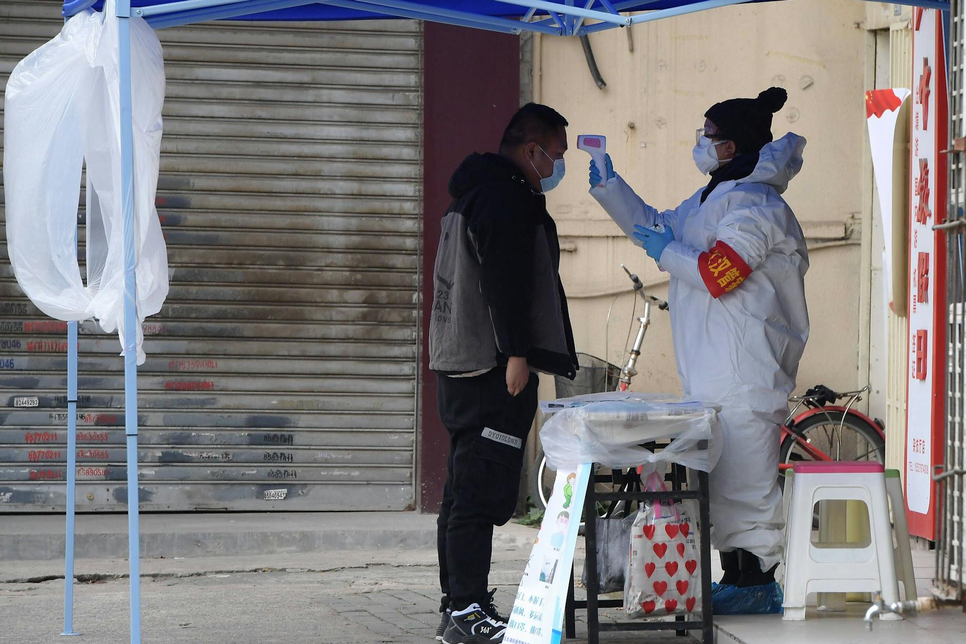 Ein Regierungsmitarbeiter misst die Temperatur eines Besuchers am Eingang eines Wohnblocks in Wuhan, Februar 2020.