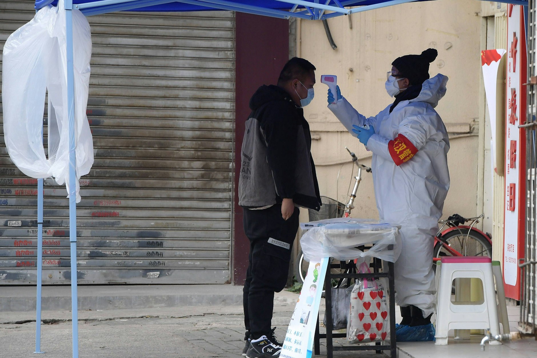 Ein Regierungsmitarbeiter misst die Temperatur eines Besuchers am Eingang eines Wohnblocks in Wuhan, Februar 2020.