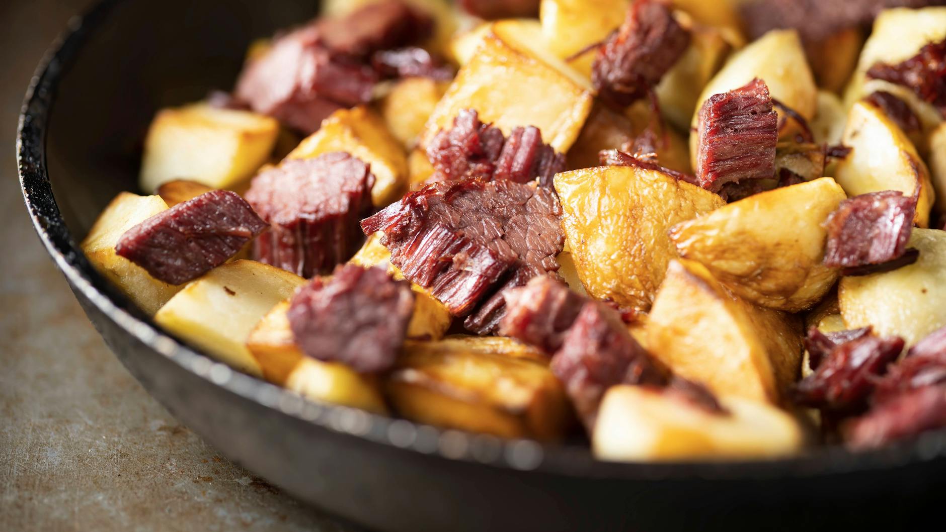 Wer Hoppel Poppel zubereiten will, brät zuerst Fleischreste und Kartoffeln in einer Pfanne an - was noch zu tun ist erfahren Sie im Rezept.