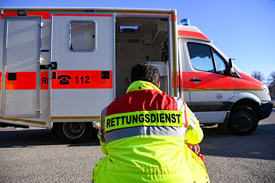 Ein erschöpfter Rettungssanitäter sitzt vor seinem Einsatzfahrzeug.