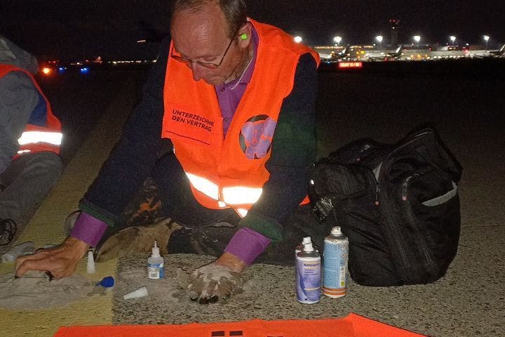 Die Aktivisten kleben sich auf dem Rollfeld des Flughafens Köln/Bonn.
