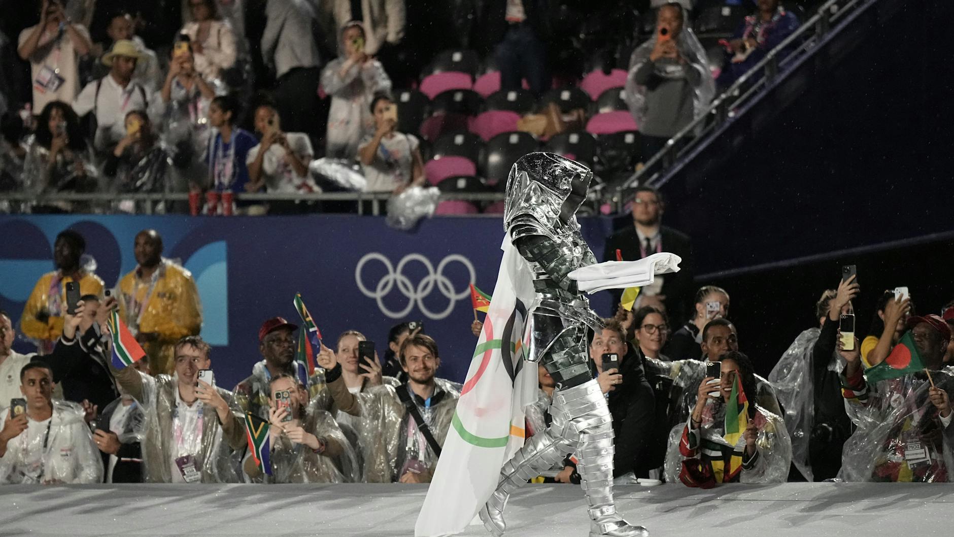 Eine Reiterin trägt die Olympia-Fahne ins Trocadéro-Stadion. Sie war zuvor auf einem Metallpferd über die Seine geritten. Die Fahne wurde falsch herum gehisst.