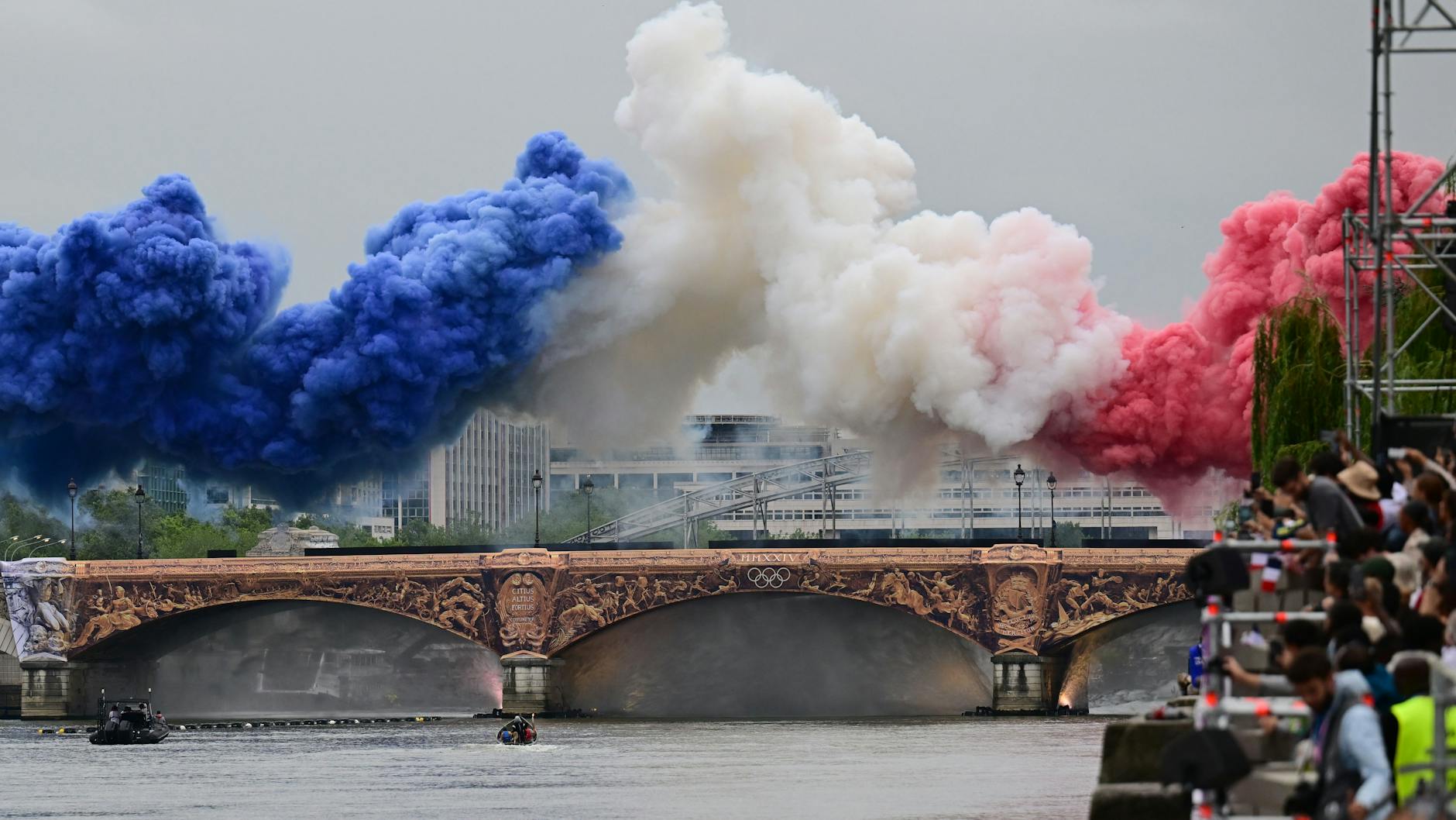 Startschuss zum Seine-Spektakel: Pyrotechnik in den Farben der französischen Nationalflagge wird über einer Seine-Brücke gezündet.