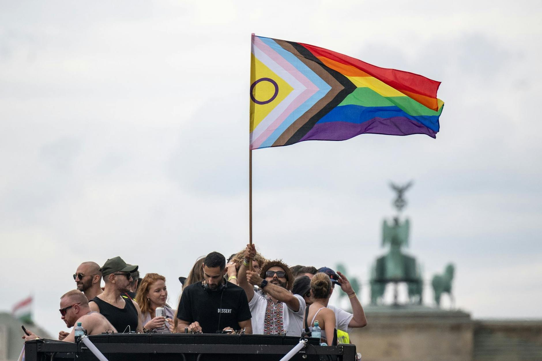 Menschen stehen mit einer Pride-Flagge auf einem Truck.