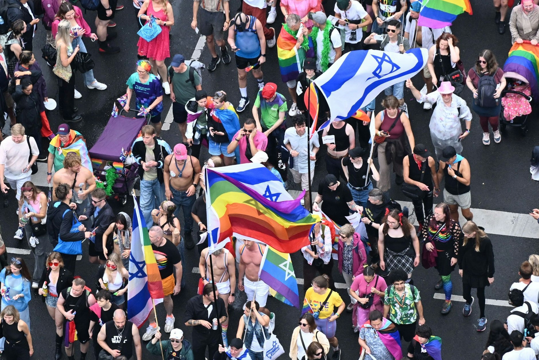 Teilnehmer halten Israel- und Regenbogen-Flaggen hoch.