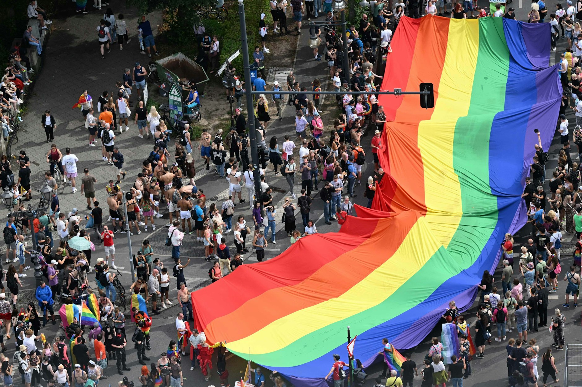 Teilnehmer tragen eine riesige Regenbogen-Flagge über den CSD.